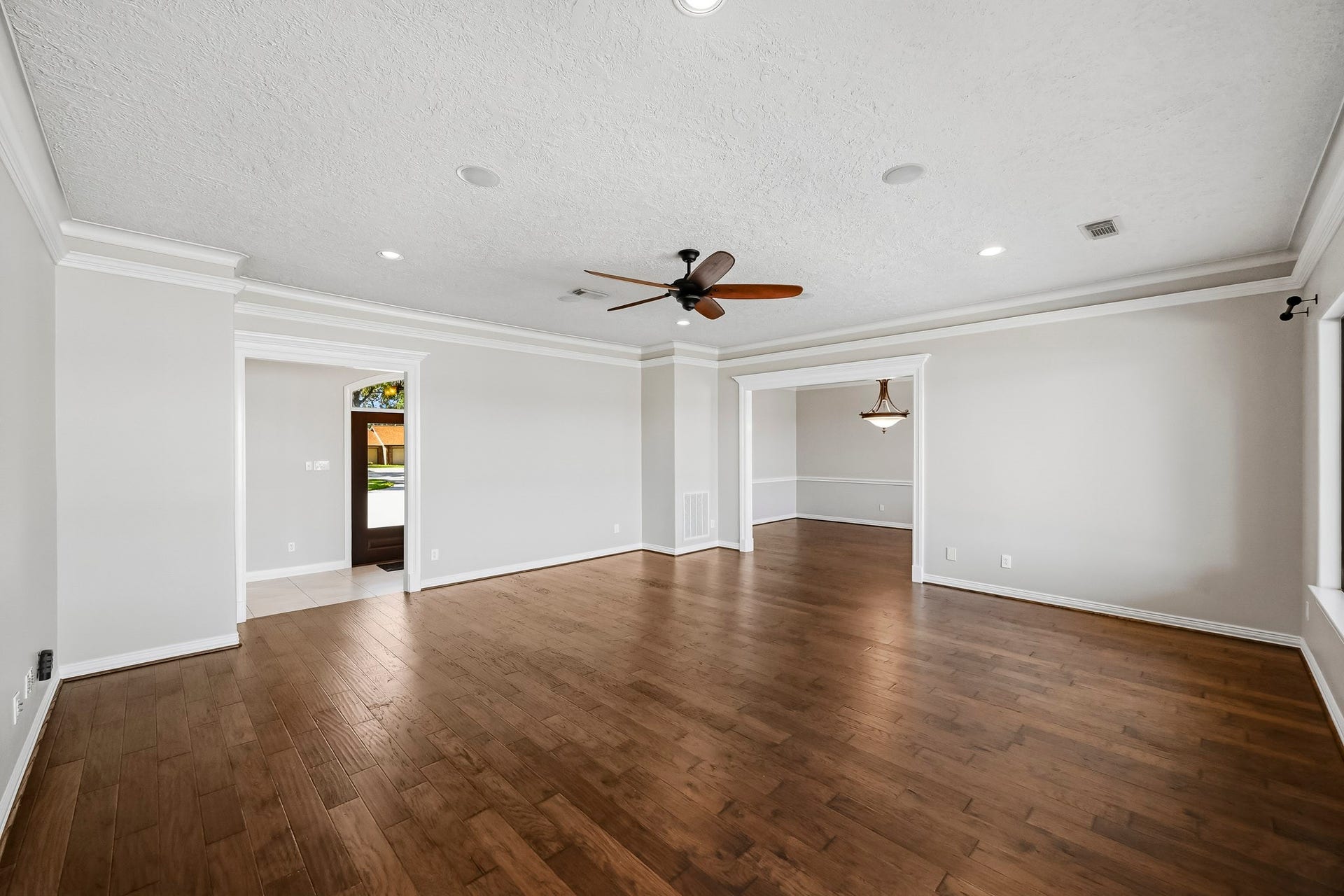 9354 Escondido Drive, Willis, TX 77318 The expansive living room showcases wood-look tile flooring, crown molding, a tray ceiling, recessed lighting and a ceiling fan.