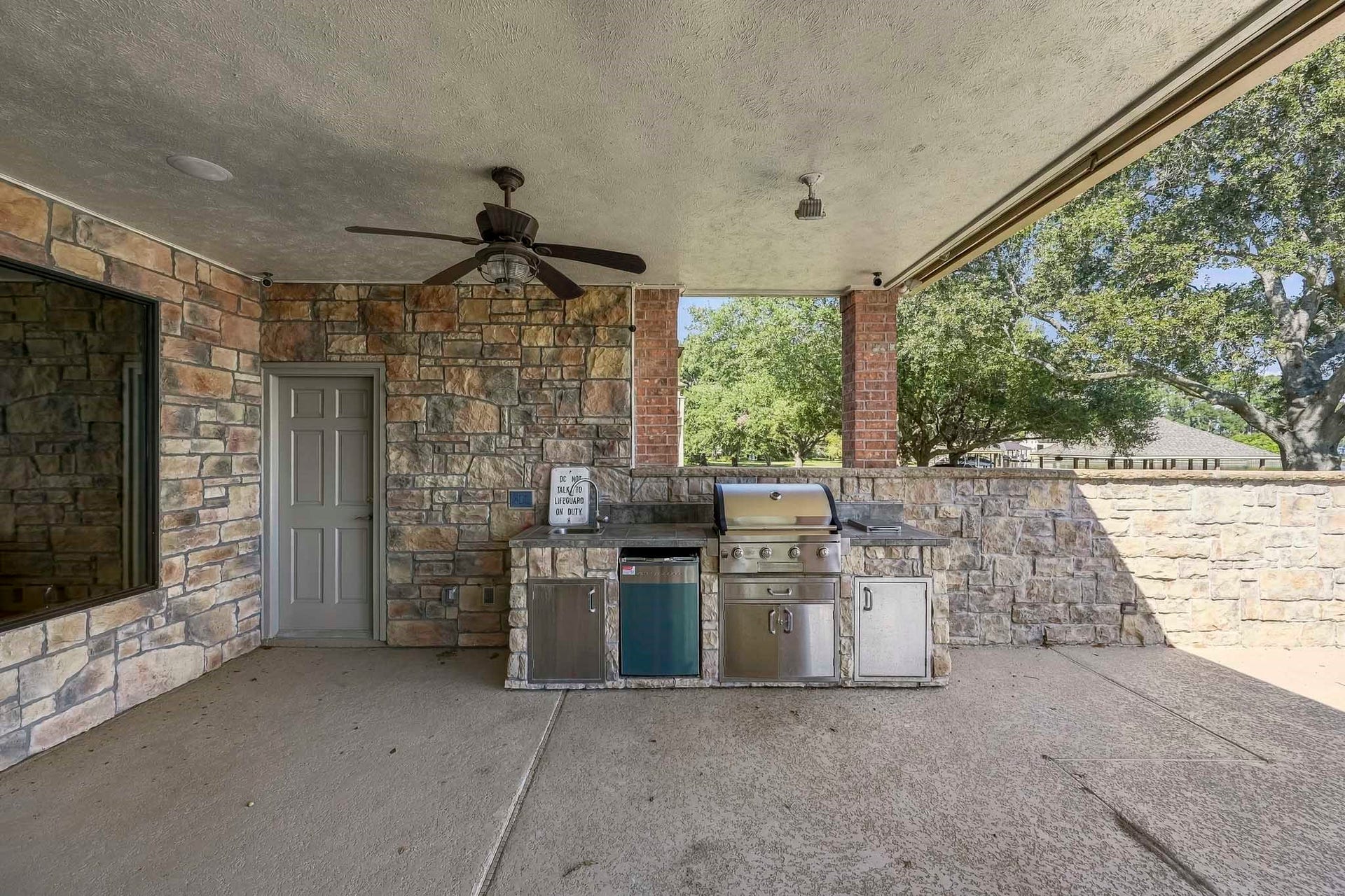 9354 Escondido Drive, Willis, TX 77318 Entertain in style with an outdoor kitchen featuring a built-in gas grill, refrigerator, generous counter space and storage. Ceiling fans and stone finishes complete the covered patio.