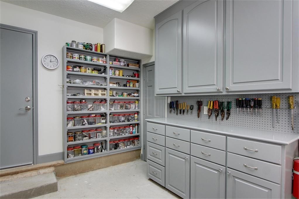9354 Escondido Drive, Willis, TX 77318 A dream space for hobbyists and DIY enthusiasts! This impressive workshop features extensive built-in cabinetry, numerous drawers, open shelving and a dedicated work surface.