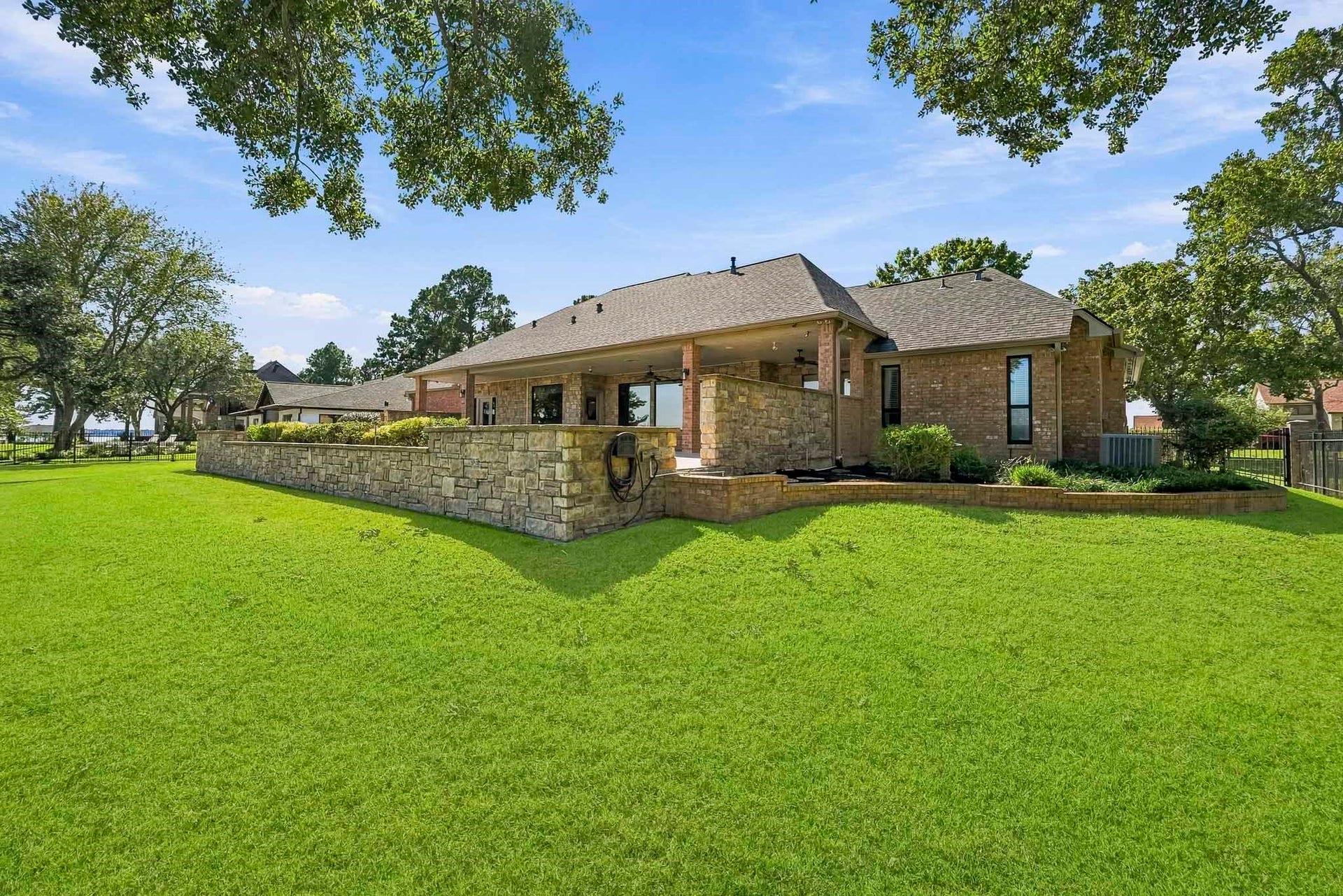 9354 Escondido Drive, Willis, TX 77318 Mature shade trees, a lush green lawn and an impressive terraced stone wall create a picturesque setting around the elevated pool and patio.