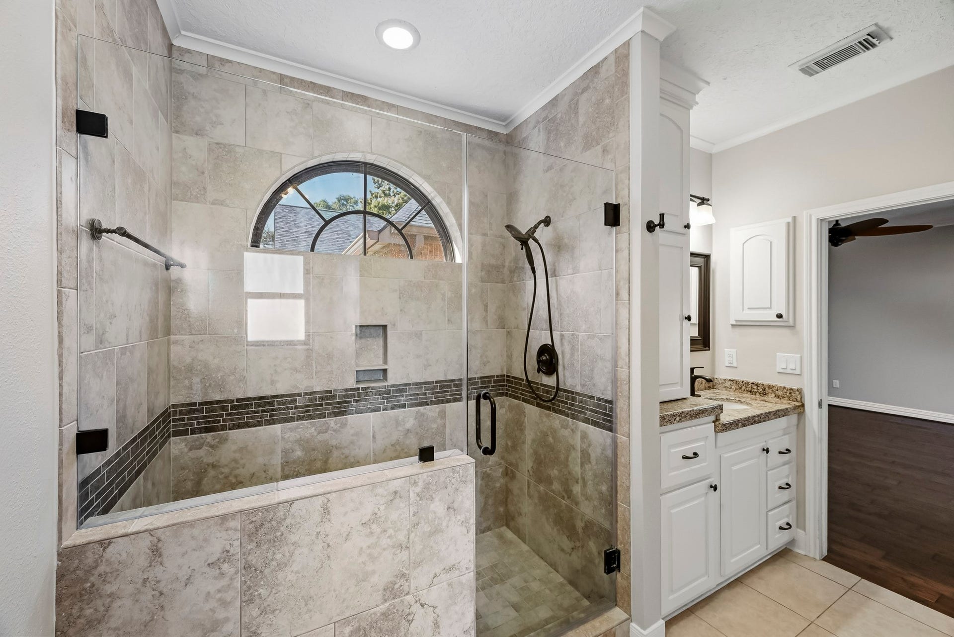 9354 Escondido Drive, Willis, TX 77318 This impressive walk-in shower features floor-to-ceiling tile, a frameless glass enclosure, decorative accents, built-in niches and an elegant arched window!