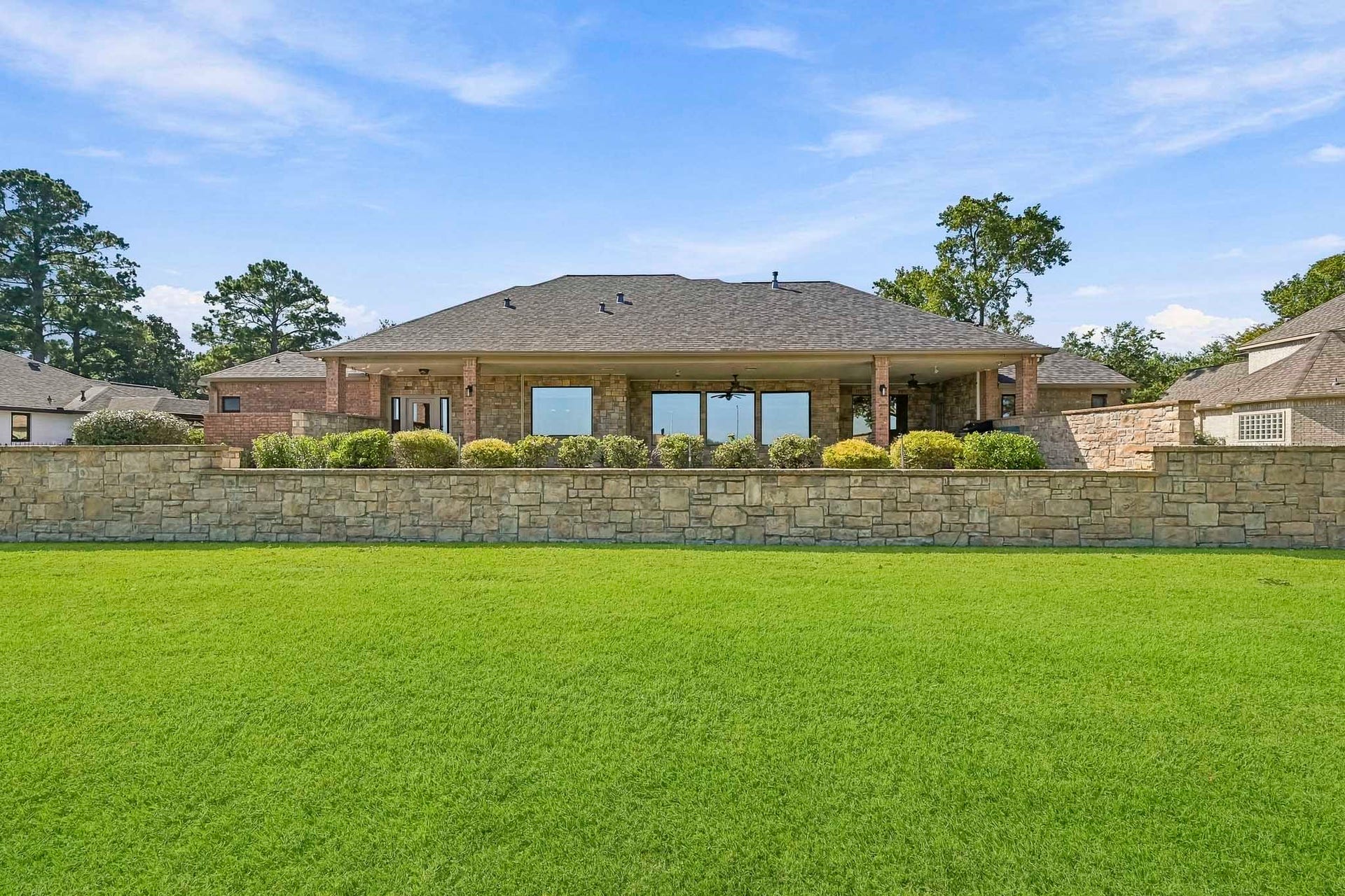9354 Escondido Drive, Willis, TX 77318 The impressive rear elevation showcases beautiful stone accents, expansive windows and the home's distinctive terraced landscaping.