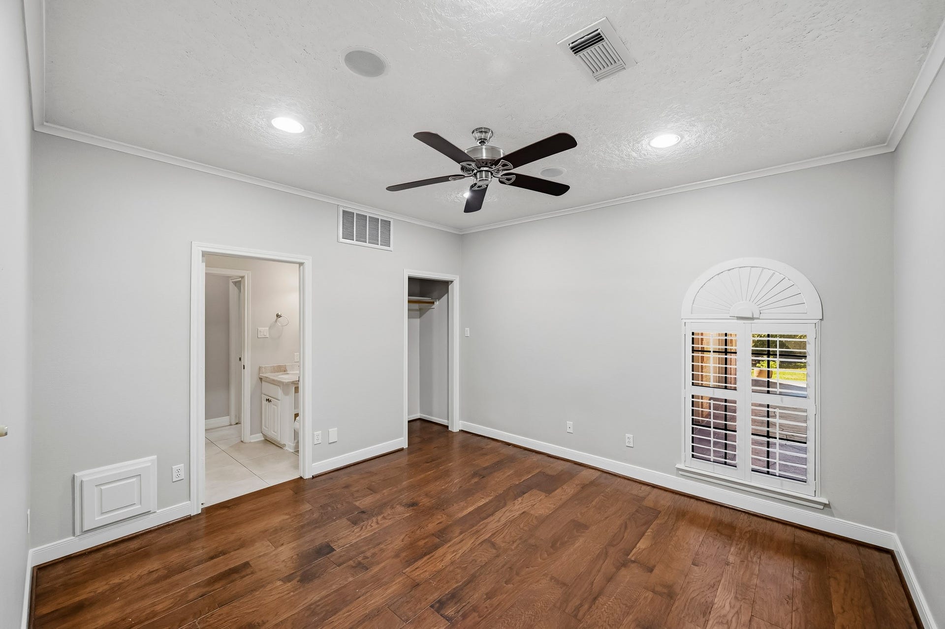 9354 Escondido Drive, Willis, TX 77318 Bedroom #2. Located near the front entry, this versatile bedroom could optionally be utilized as a study. It features recessed lighting, a ceiling fan and a charming arched window with plantation shutters.