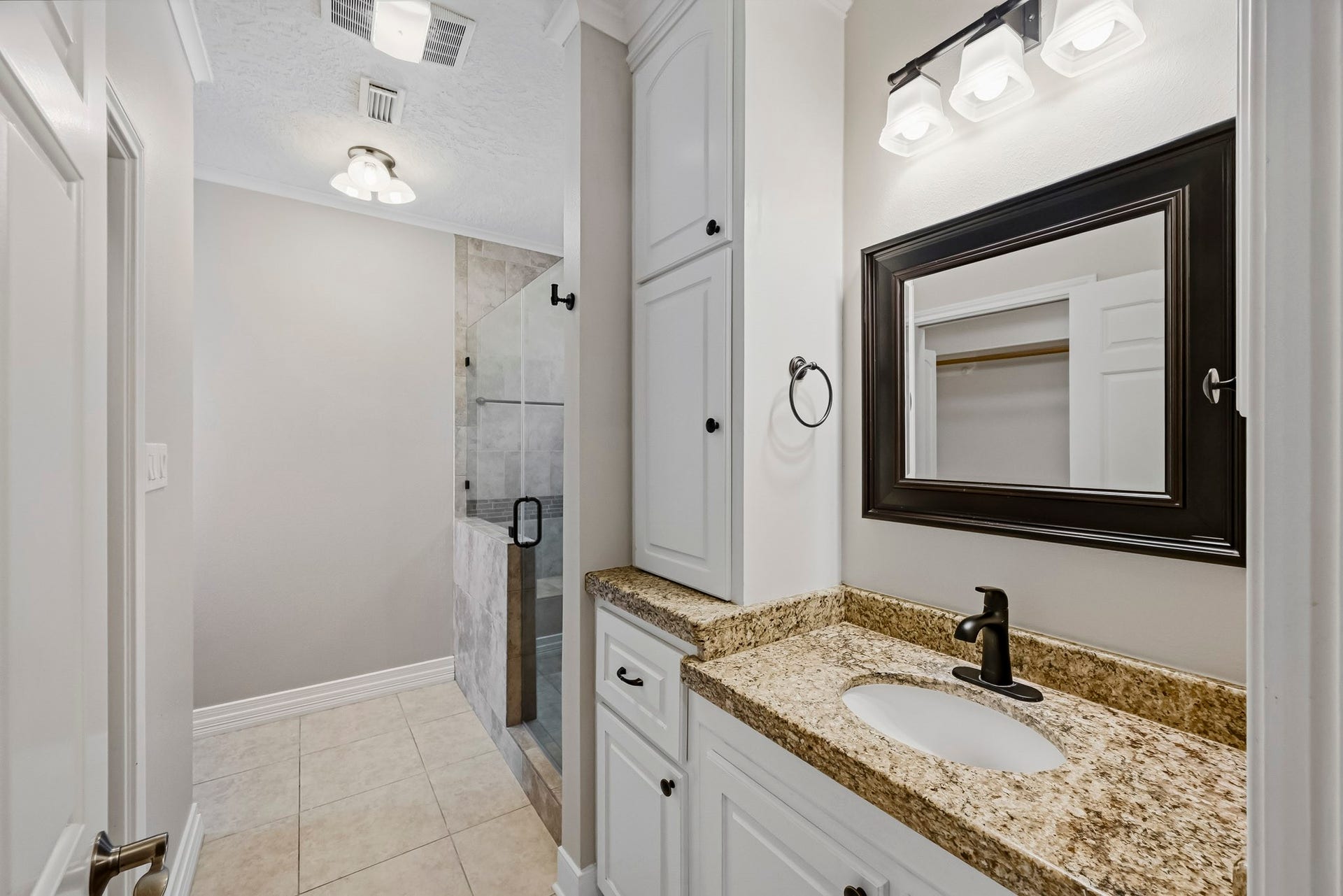 9354 Escondido Drive, Willis, TX 77318 The second primary bathroom features a granite-topped vanity, updated fixtures, generous cabinetry and a beautifully tiled walk-in shower.