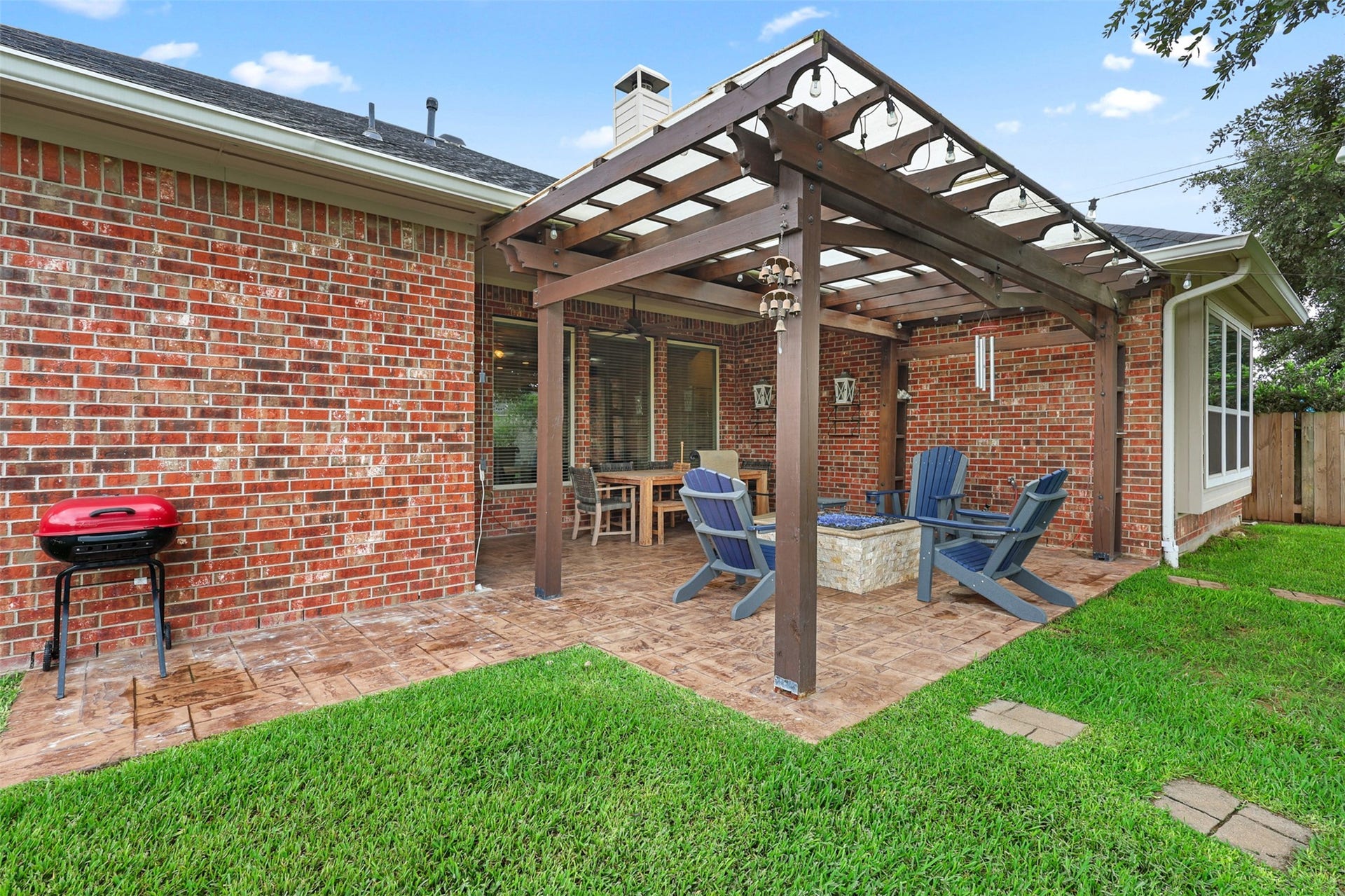 2902 Red Maple Drive, Katy, TX 77494 The pergola-style patio creates an inviting outdoor living space complete with decorative lighting, a built-in fire feature, and ample space for both dining and conversation areas.