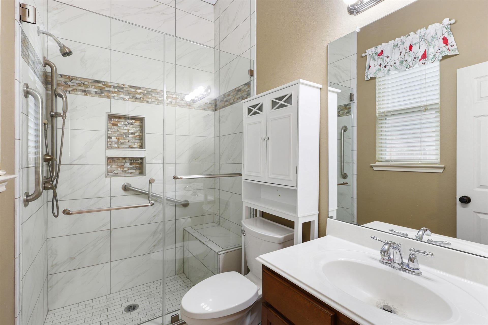2902 Red Maple Drive, Katy, TX 77494 The beautifully remodeled ensuite bathroom showcases a spacious walk-in shower with frameless glass enclosure, floor-to-ceiling designer tile, decorative accent bands, built-in niches, and a convenient bench seat.