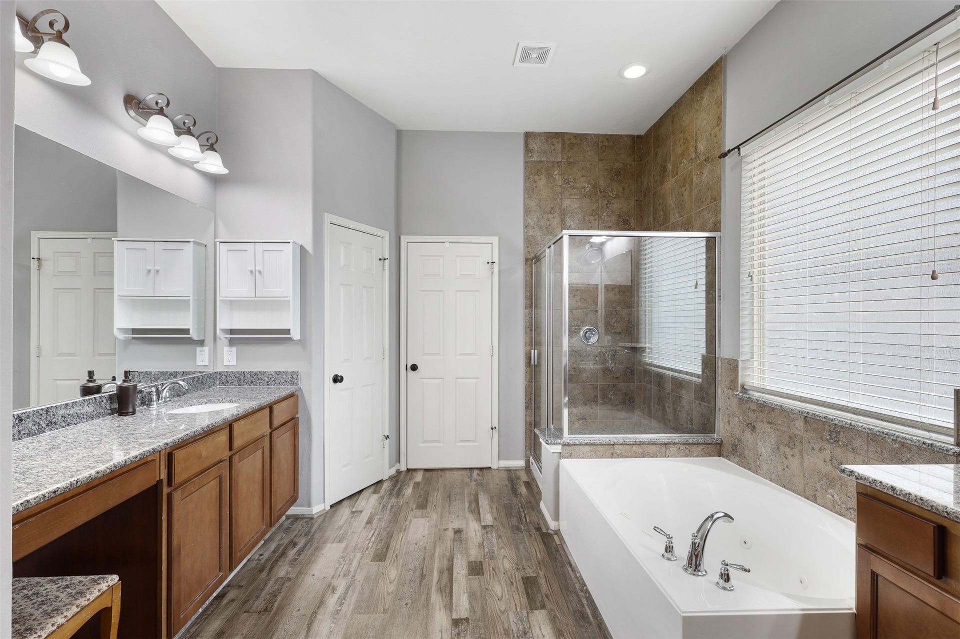 2902 Red Maple Drive, Katy, TX 77494 The spa-inspired primary bathroom is thoughtfully designed to provide both luxury and functionality. A long granite-topped vanity offers abundant counter space and storage, while rich cabinetry, & updated lighting.