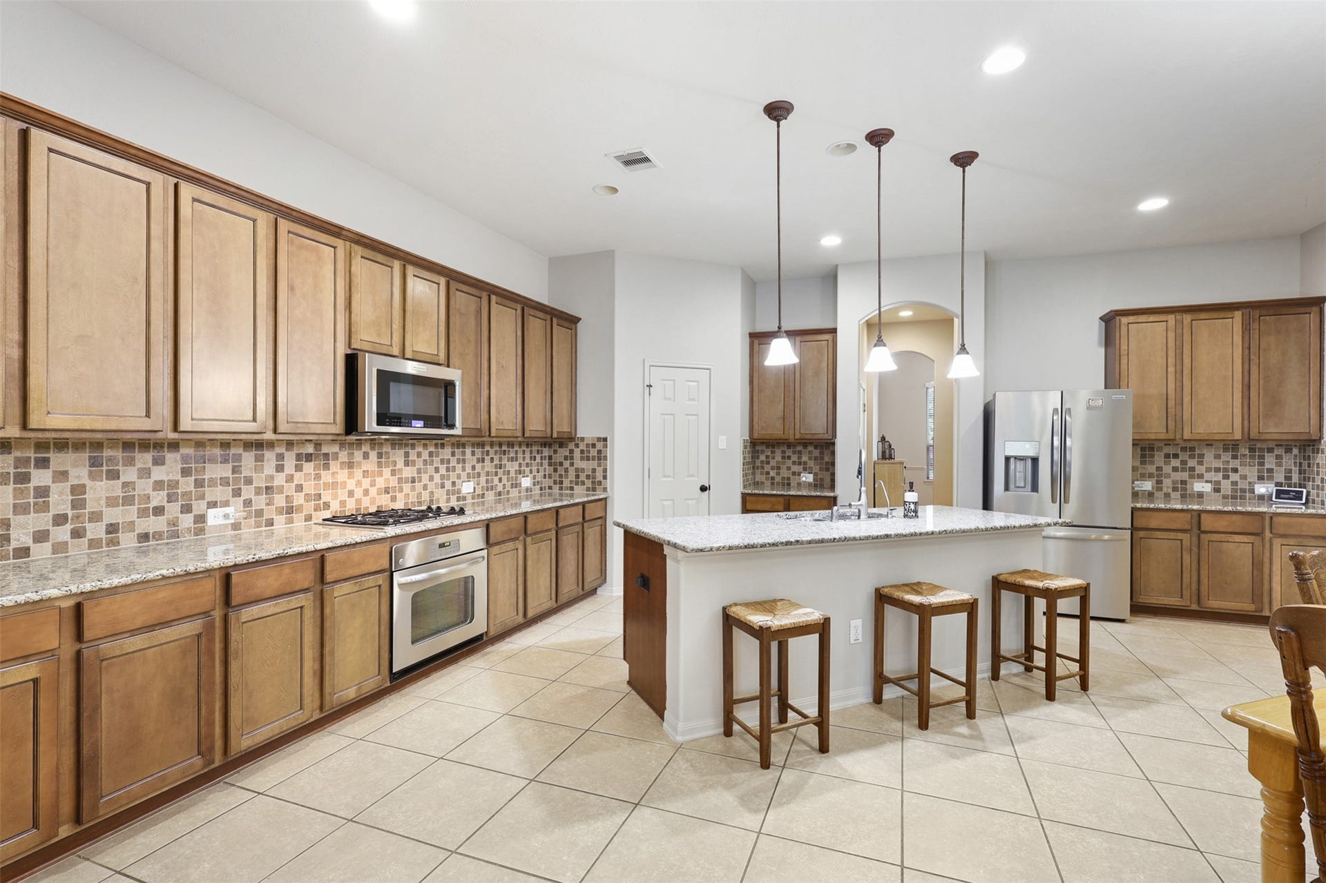 2902 Red Maple Drive, Katy, TX 77494 Rich wood cabinetry provides abundant storage, while granite countertops and an attractive mosaic tile backsplash add warmth and sophistication. Stainless steel appliances, a gas cooktop, under-cabinet lighting, and extensive counter space make meal preparation effortless.