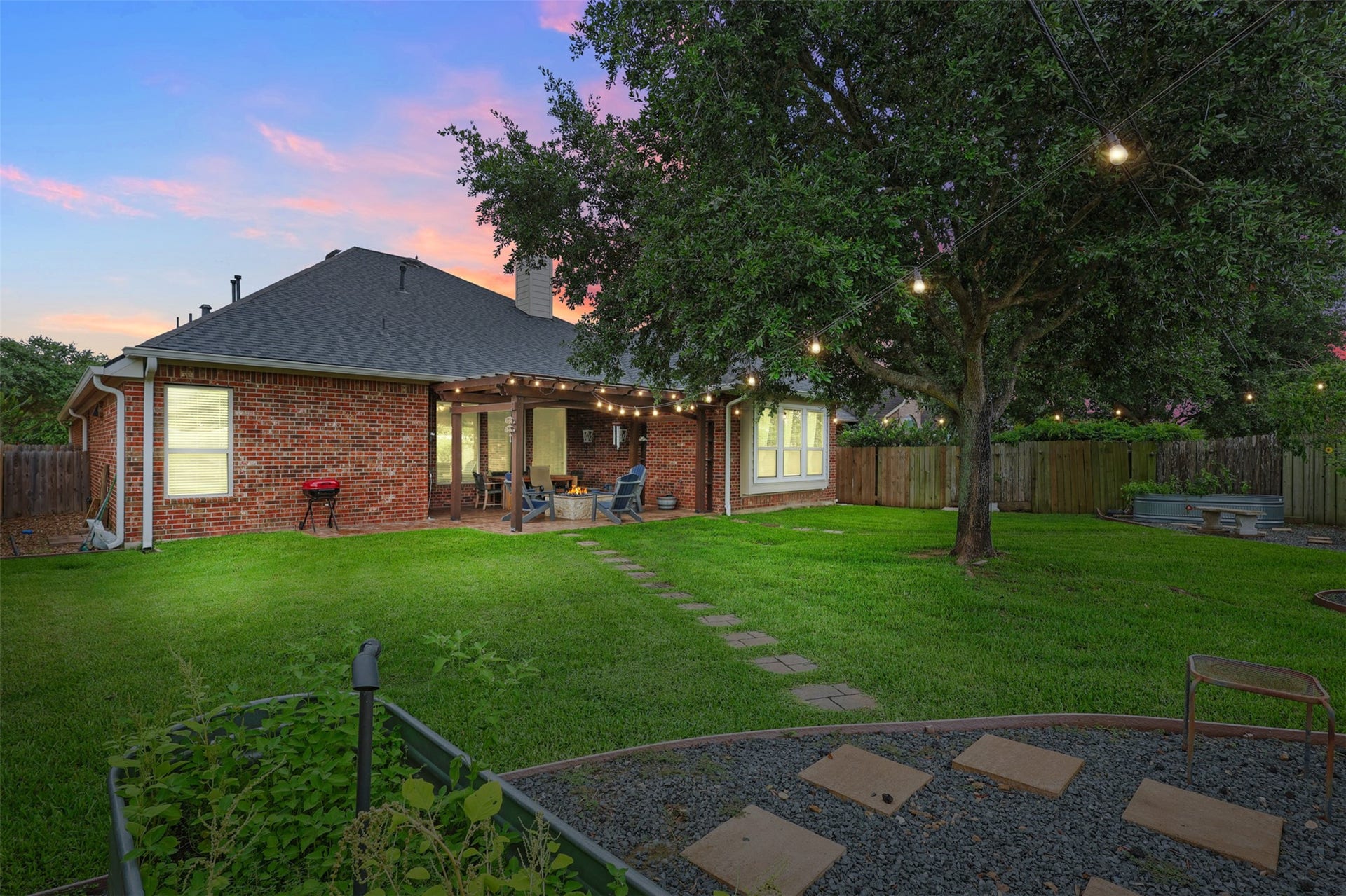 2902 Red Maple Drive, Katy, TX 77494 As the sun sets, the backyard transforms into a peaceful retreat. String lighting draped beneath mature shade trees creates a warm ambiance while the expansive lawn provides plenty of room for outdoor games, pets, or future backyard enhancements.