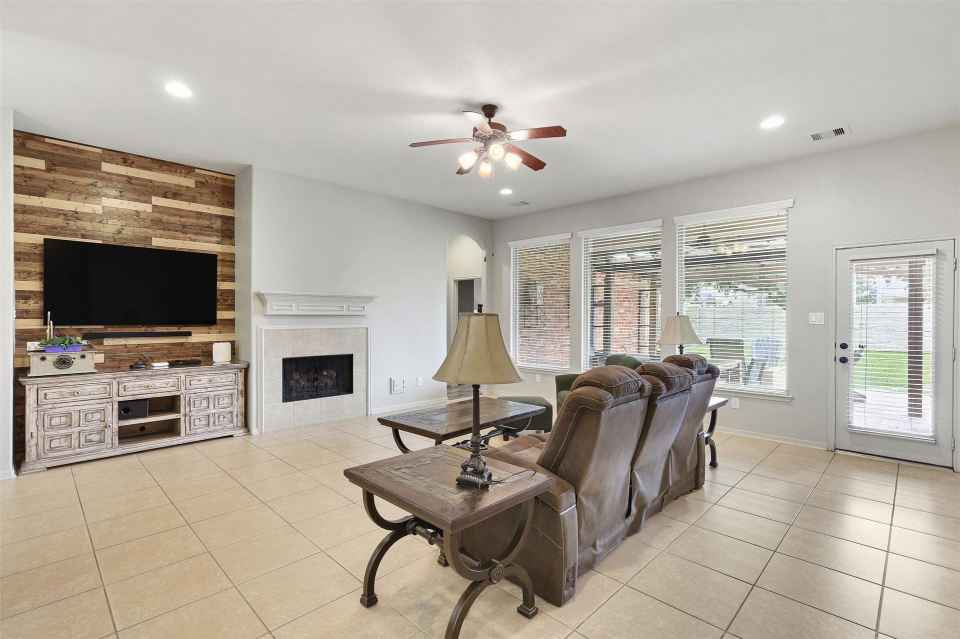 2902 Red Maple Drive, Katy, TX 77494 The spacious family room is designed for both everyday comfort & effortless entertaining. A cozy gas-log fireplace with an elegant mantel creates a warm focal point, while a custom wood accent wall & entertainment nook add character & style. Large windows & a glass back door fill the room with natural light.