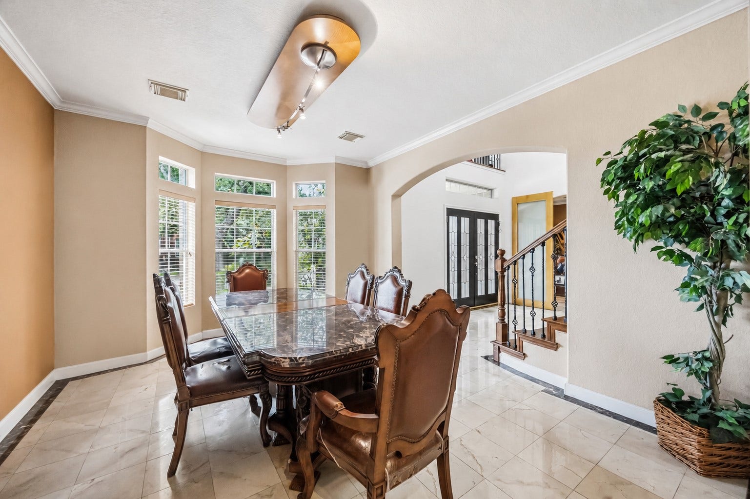 7610 Guinevere Drive, Sugar Land, TX 77479 Highlighting an open architectural flow, this dining space includes a bay window alcove, a wide archway opening to the foyer, and a peek at the decorative staircase banister.