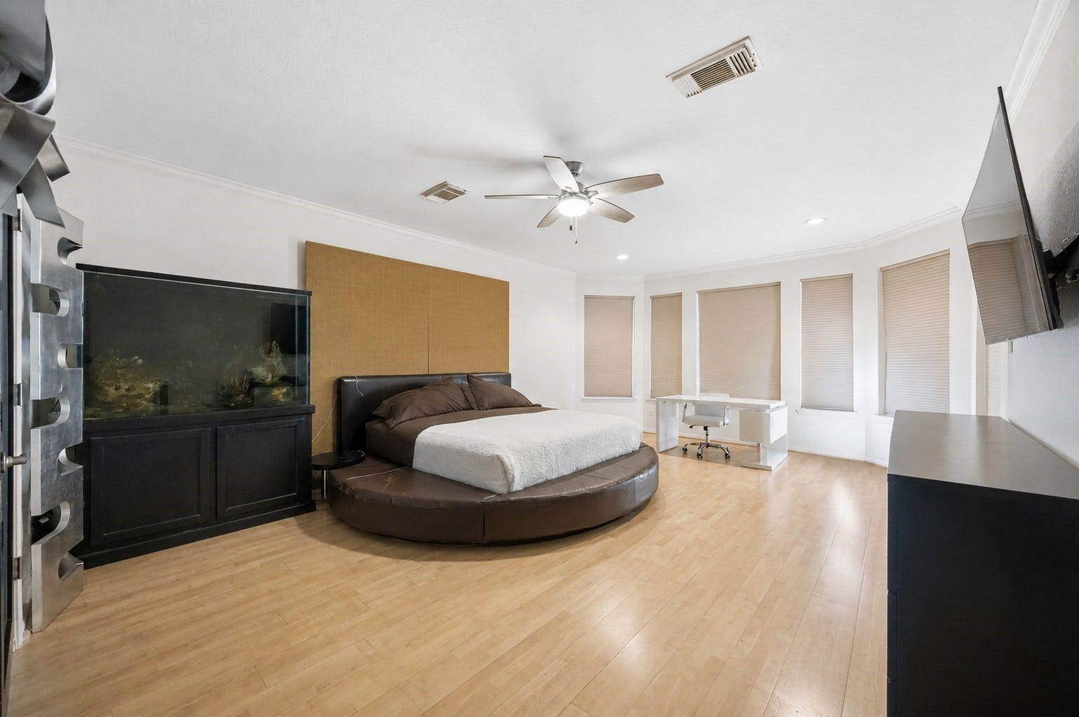 7610 Guinevere Drive, Sugar Land, TX 77479 The spacious primary bedroom features smooth wood flooring, a central ceiling fan, and a curved bay window layout that welcomes natural light.