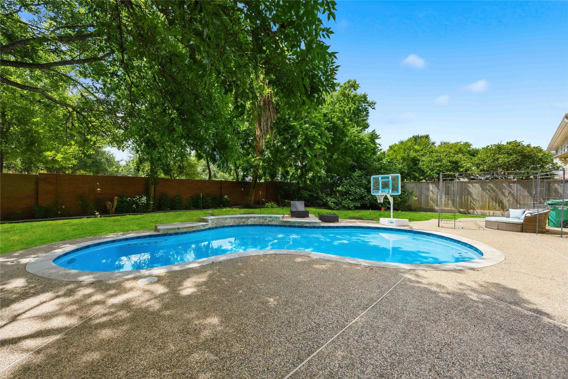 7610 Guinevere Drive, Sugar Land, TX 77479 The resort-style backyard layout includes a multi-level pool coping design accented by tile work along the water line.