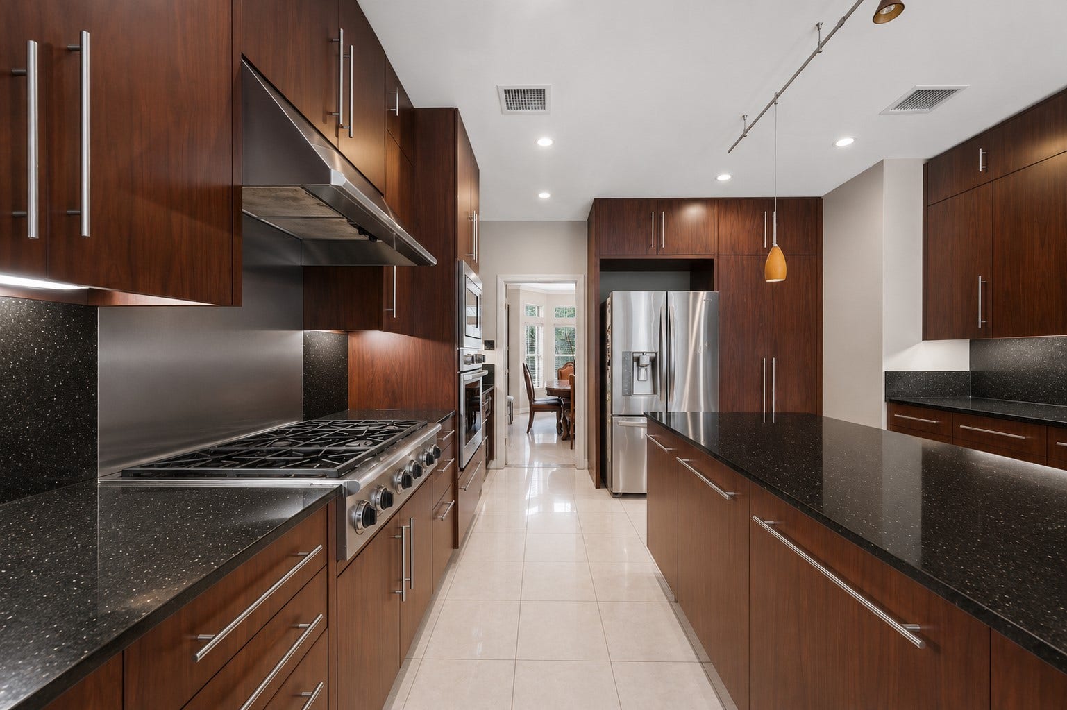 7610 Guinevere Drive, Sugar Land, TX 77479 This sleek culinary space features premium stainless steel appliances, a professional-grade gas range with a matching vent hood, and a continuous stone backsplash.