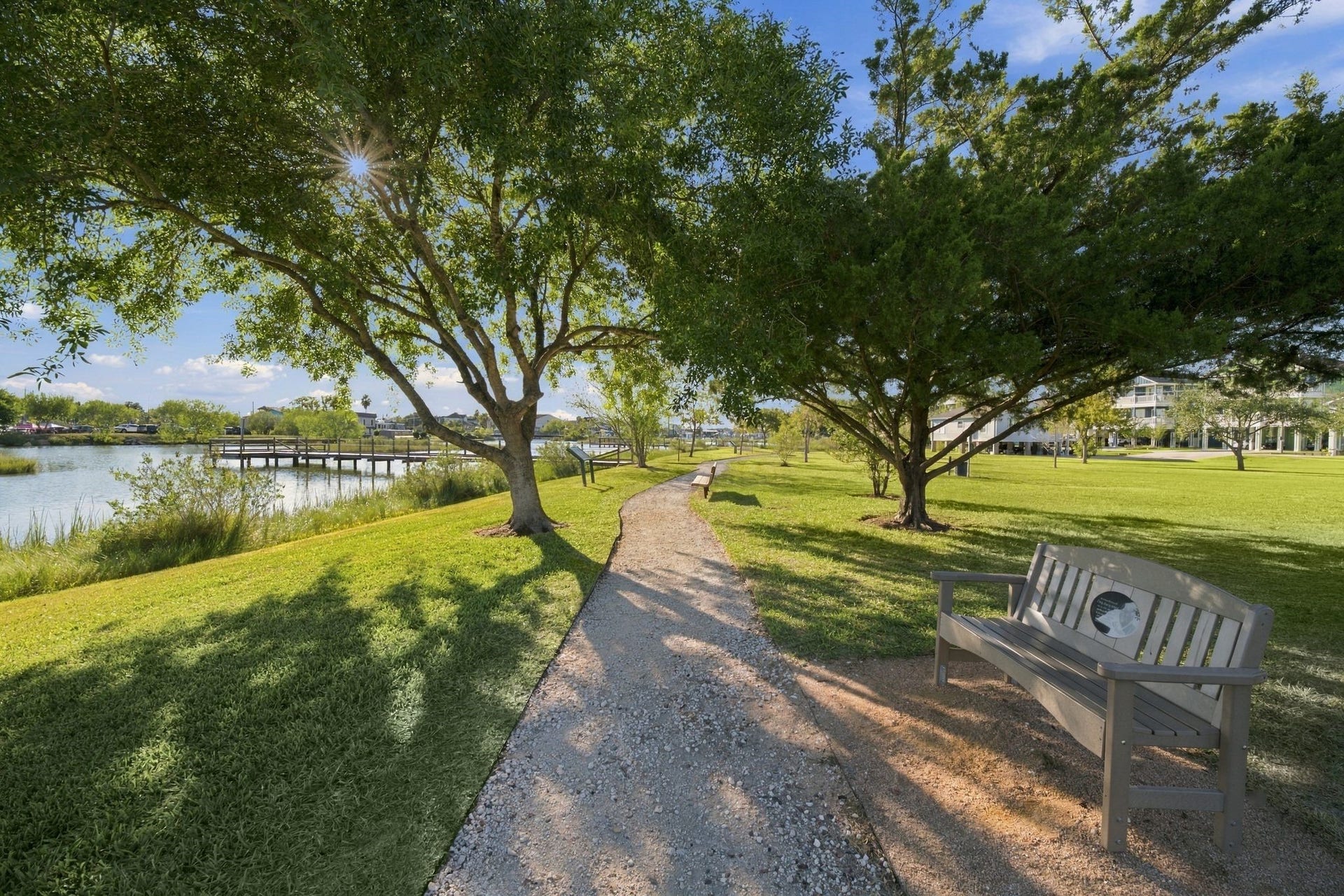 10 Harbor Lane, Kemah, TX 77565 A serene pathway winds through one of the many parks offering picturesque views of a tranquil lake and a charming wooden dock.