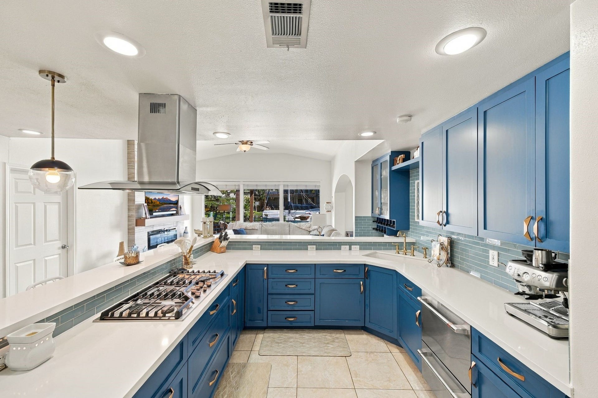 10 Harbor Lane, Kemah, TX 77565 A modern kitchen featuring bold blue cabinetry, sleek countertops, double ovens, and a built-in gas cooktop. The open layout flows into a cozy living area, enhanced by ample natural light.
