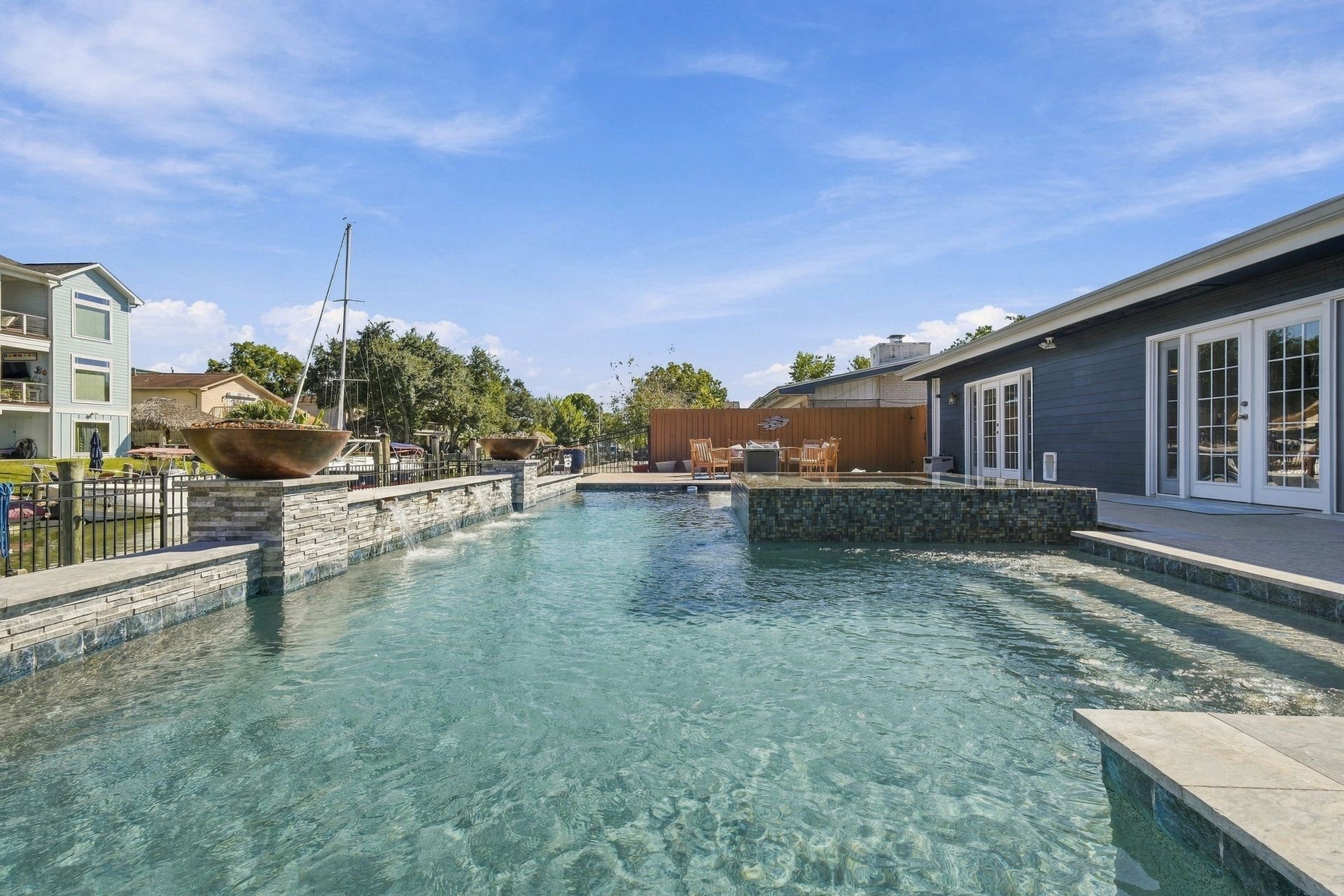 10 Harbor Lane, Kemah, TX 77565 Luxurious outdoor oasis featuring a sparkling pool with a stone-accented edge, complemented by a spacious patio and modern landscaping, perfect for relaxing and entertaining.