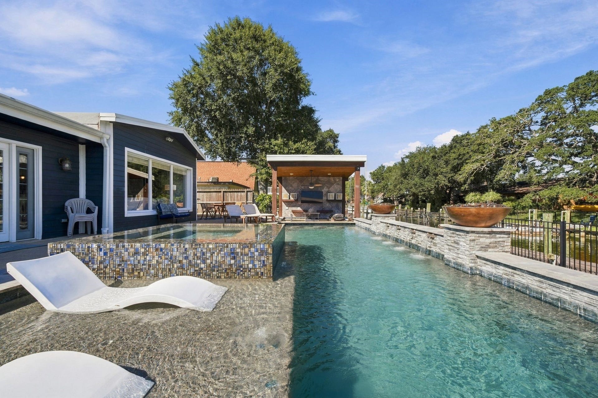 10 Harbor Lane, Kemah, TX 77565 Experience luxury outdoor living with this stunning pool area, featuring a sleek modern design, sun loungers, and a covered outdoor kitchen.