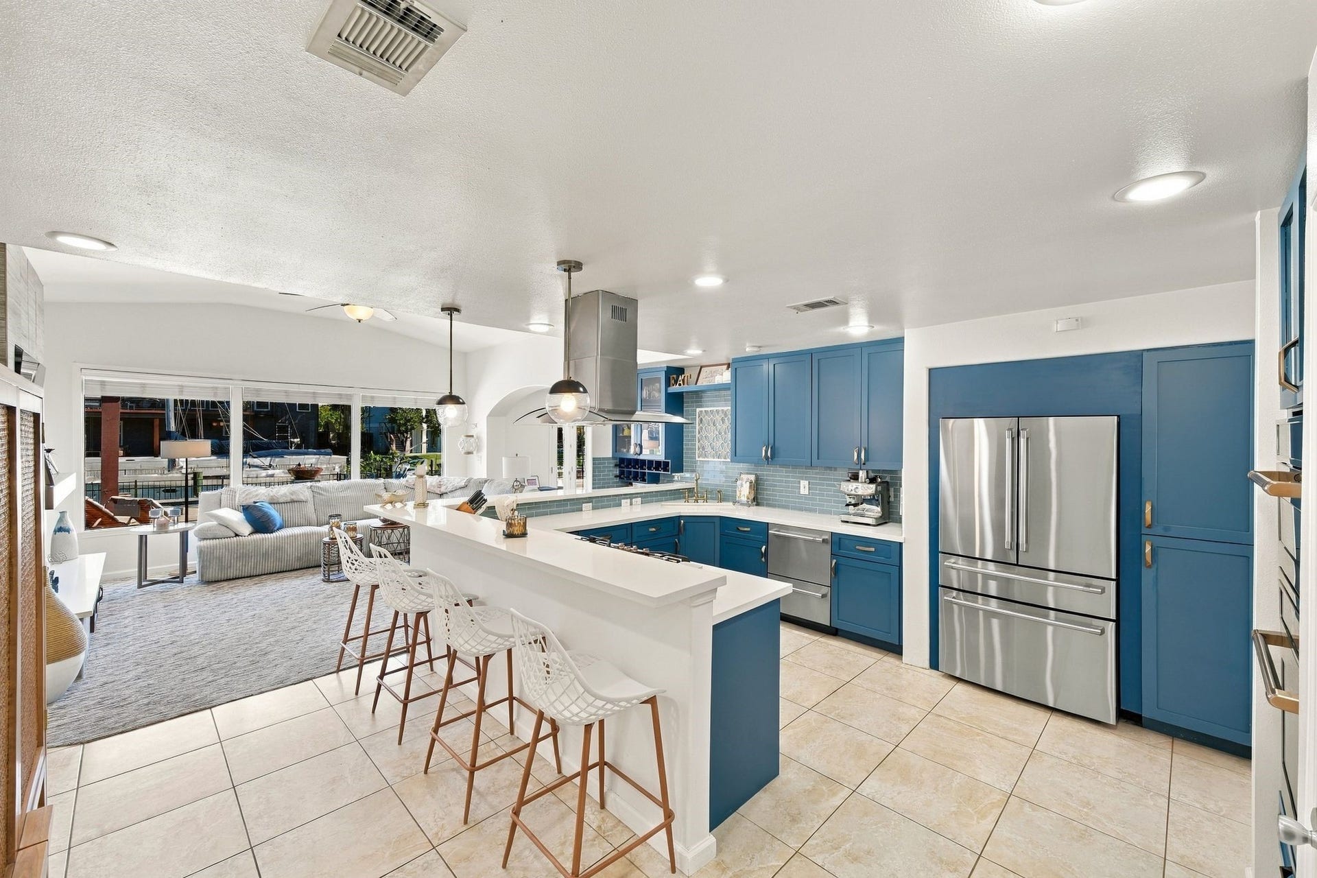 10 Harbor Lane, Kemah, TX 77565 Spacious kitchen featuring sleek blue cabinetry, modern stainless steel appliances, and a convenient breakfast bar with stylish seating.