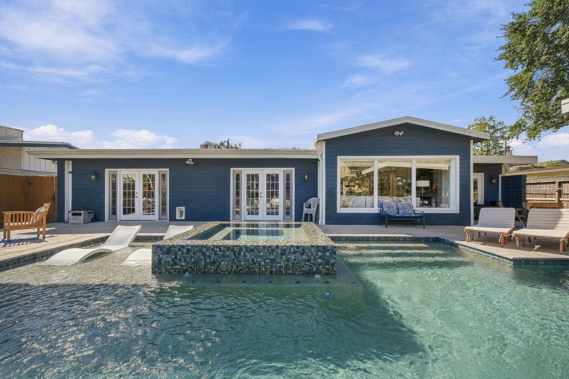 10 Harbor Lane, Kemah, TX 77565 Modern home with a stunning backyard retreat, featuring a sparkling pool, integrated spa, and stylish patio area, and outdoor kitchen, perfect for relaxation and entertainment.