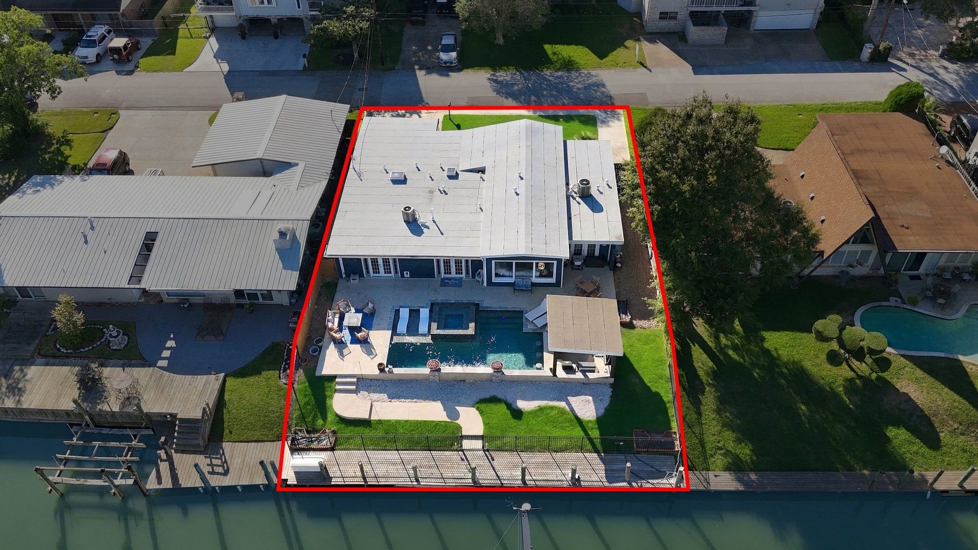 10 Harbor Lane, Kemah, TX 77565 Spacious waterfront property featuring a modern outdoor oasis with a pool, shaded patio, and direct access to the canal.