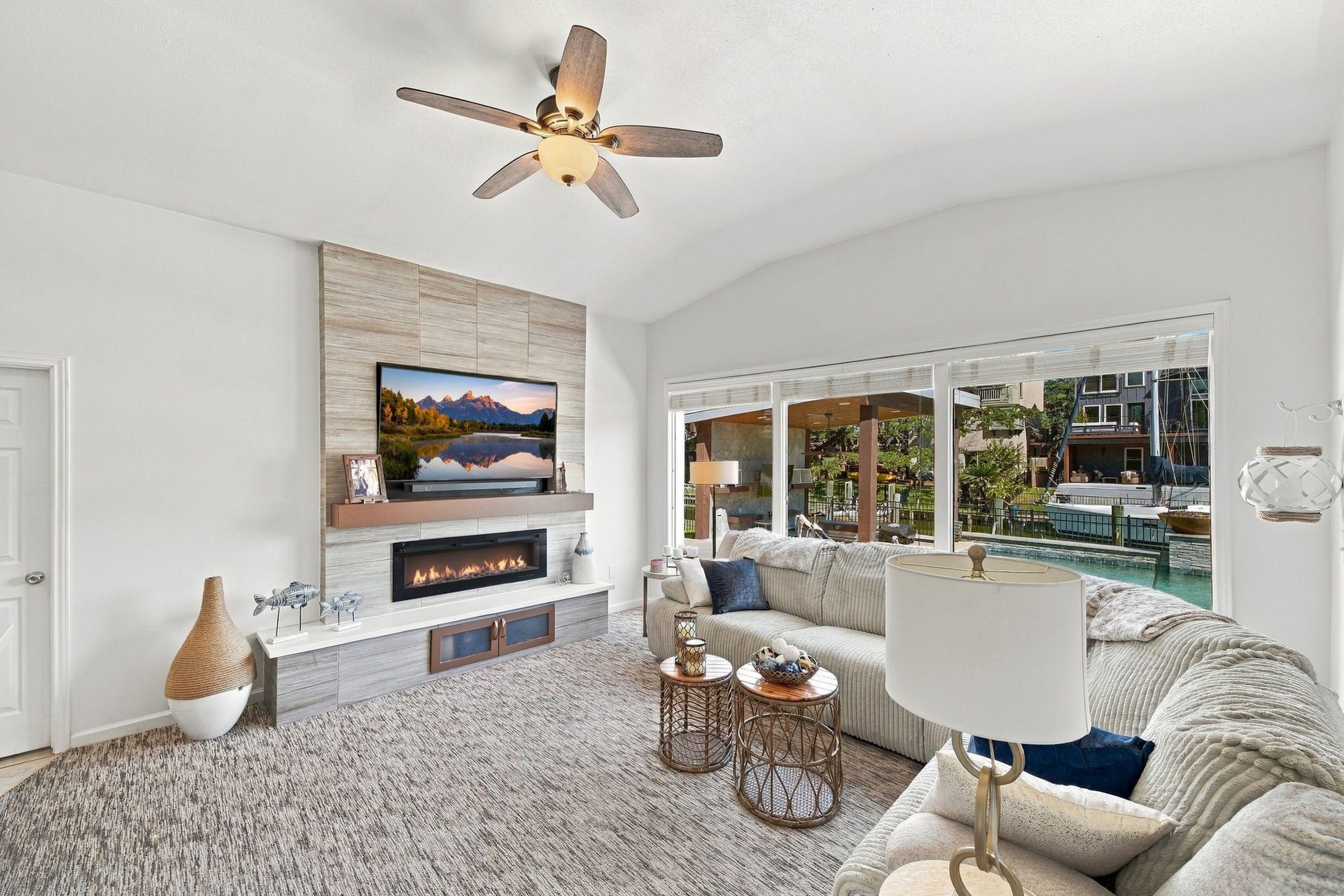 10 Harbor Lane, Kemah, TX 77565 The living room features a modern fireplace, cozy sectional seating, and expansive windows offering stunning waterfront views.