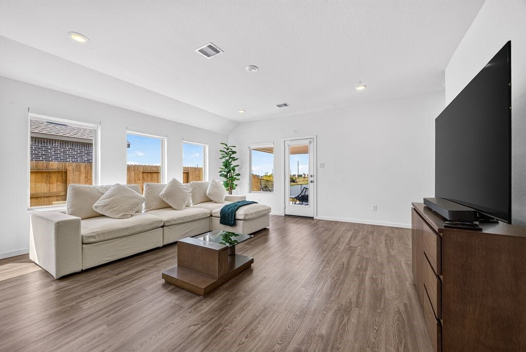5438 Still Meadow Lane, Richmond, TX 77469 Sun-Drenched Living Space: An impressively proportioned family room bathed in vibrant natural light, offering an airy, welcoming atmosphere with a direct layout connection to the kitchen.