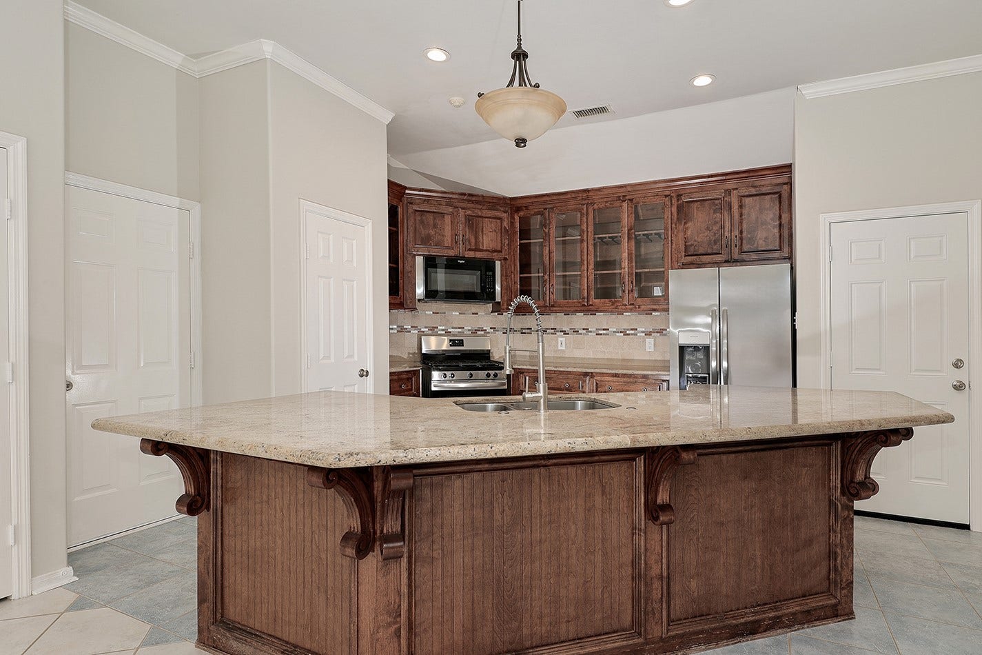 34 Cypress Bayou Court, The Woodlands, TX 77382 This modern kitchen features a spacious island with a granite countertop, elegant wood cabinetry, stainless steel appliances, and ample storage. Ideal for cooking and entertaining.