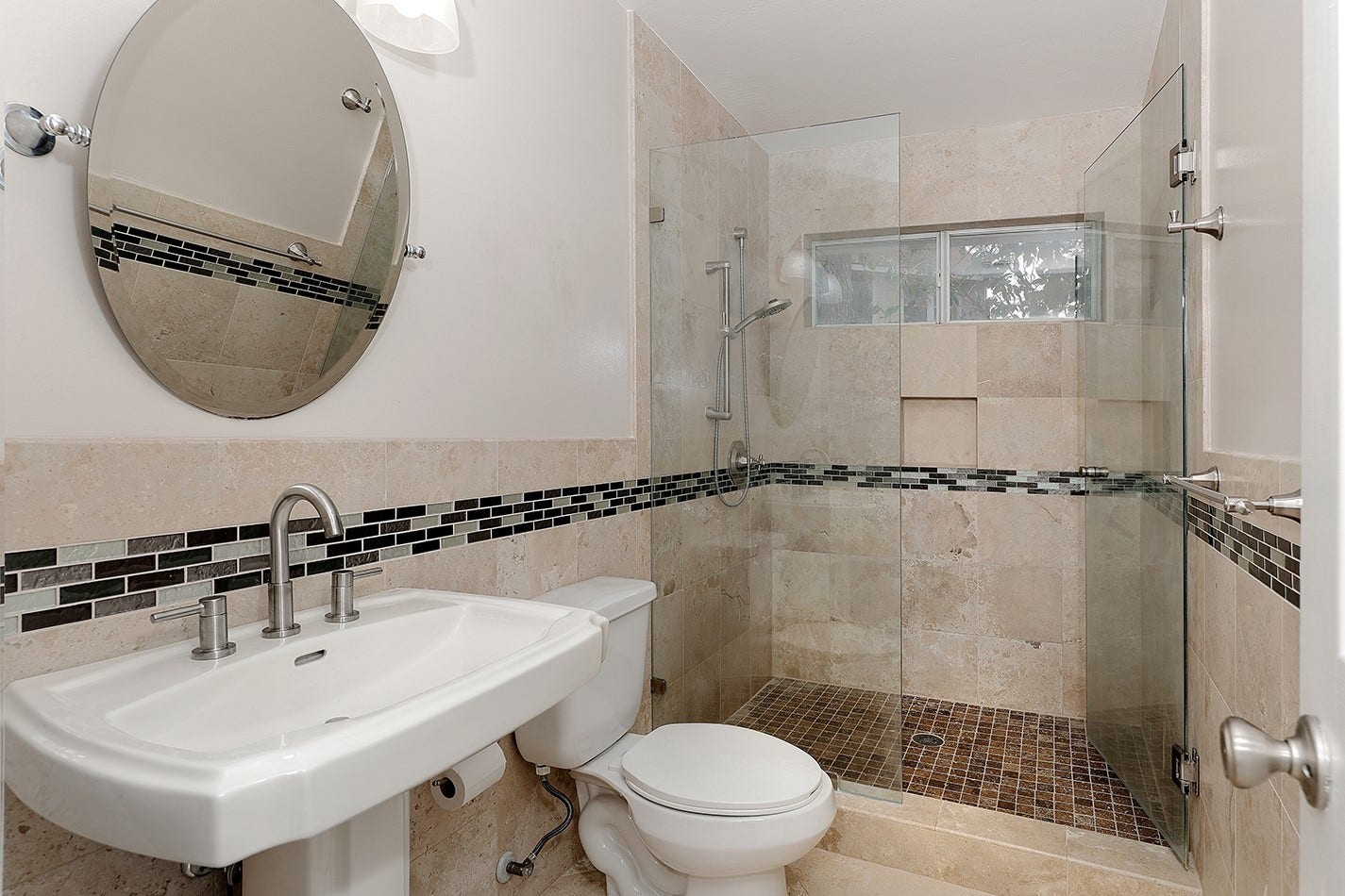 34 Cypress Bayou Court, The Woodlands, TX 77382 Modern bathroom featuring a glass-enclosed shower with stylish tile accents, a sleek pedestal sink, and a round mirror.