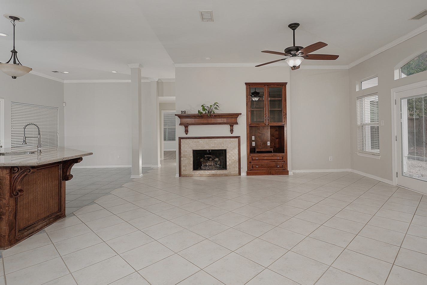 34 Cypress Bayou Court, The Woodlands, TX 77382 Bright and spacious open-concept living area with tile flooring, a central fireplace with a wooden mantel and built-in shelving.