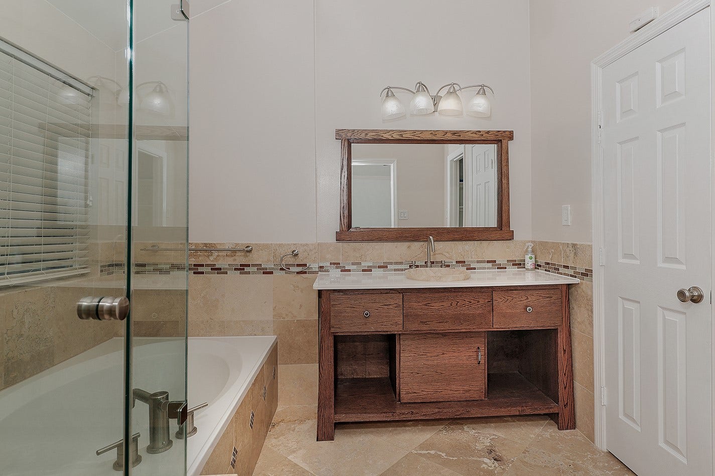 34 Cypress Bayou Court, The Woodlands, TX 77382 This bathroom features a modern design with a glass-enclosed bathtub, a wooden vanity with a large mirror, and elegant tile accents.
