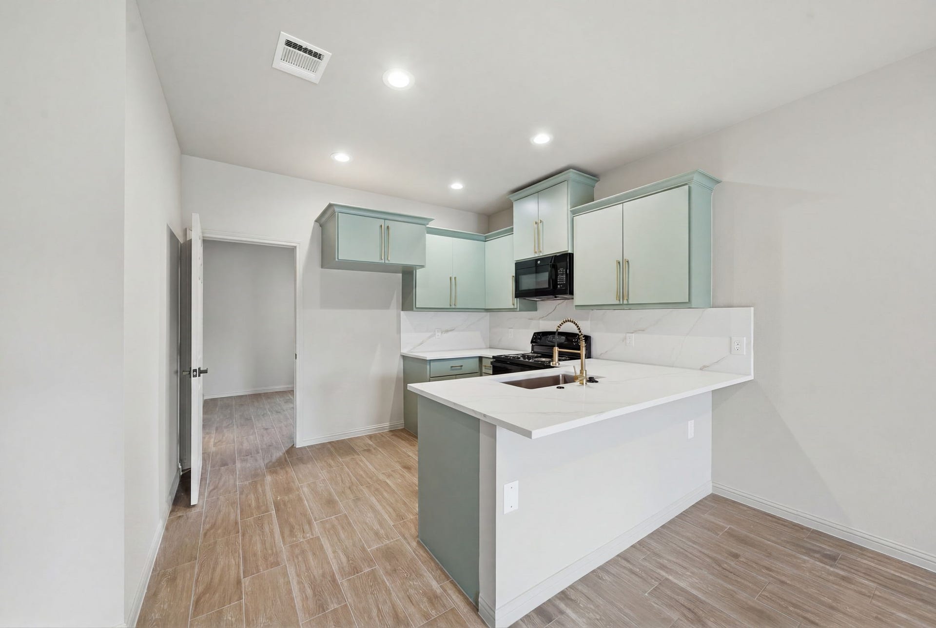 Thoughtfully designed kitchen offers abundant cabinetry, quartz surfaces, and a functional peninsula overlooking the living area.