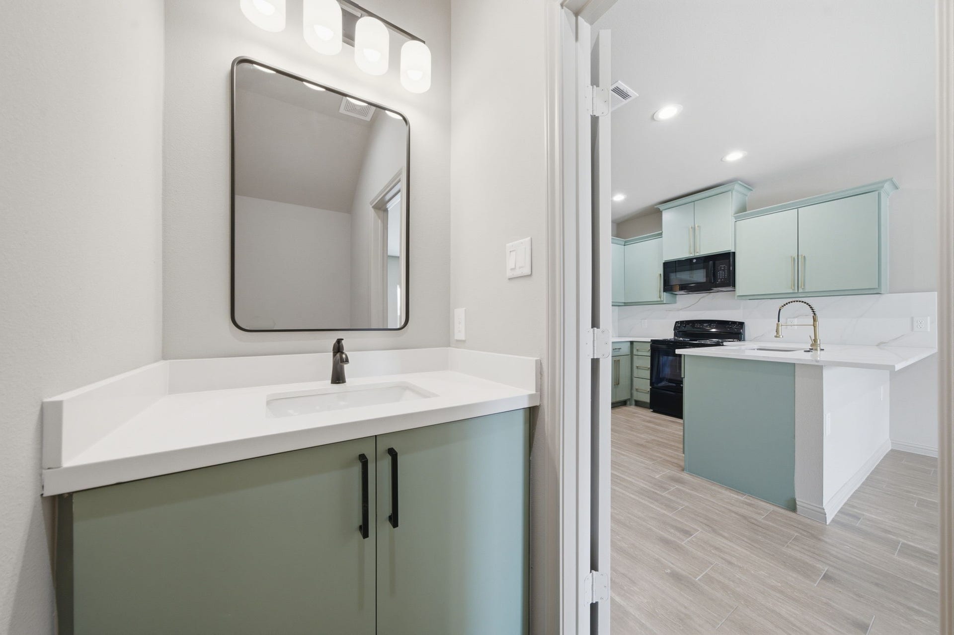 Stylish powder room off living area offers a quartz vanity, modern fixtures and a cohesive design that compliments the adjoining kitchen.