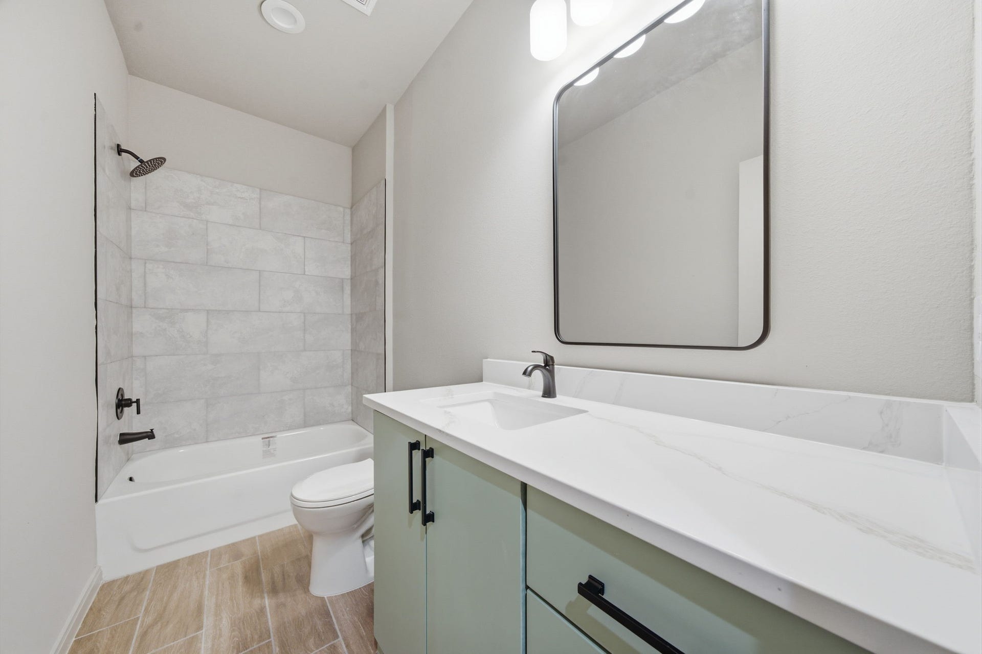 Stylish secondary bath pairs a quartz vanity with contemporary finishes and a full tub/shower combo.