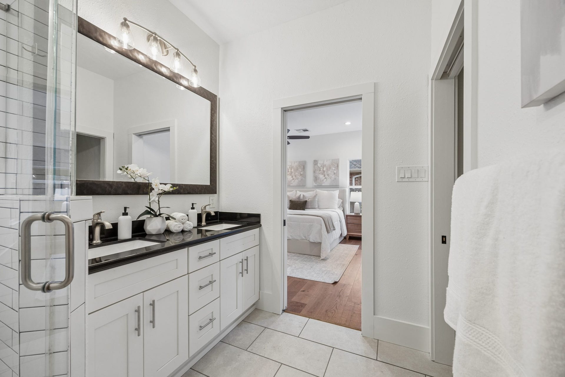 711 4th Street, Sealy, TX 77474 Primary bathroom features a double vanity with sleek black countertops, modern fixtures, and ample storage, seamlessly connected to a cozy bedroom.