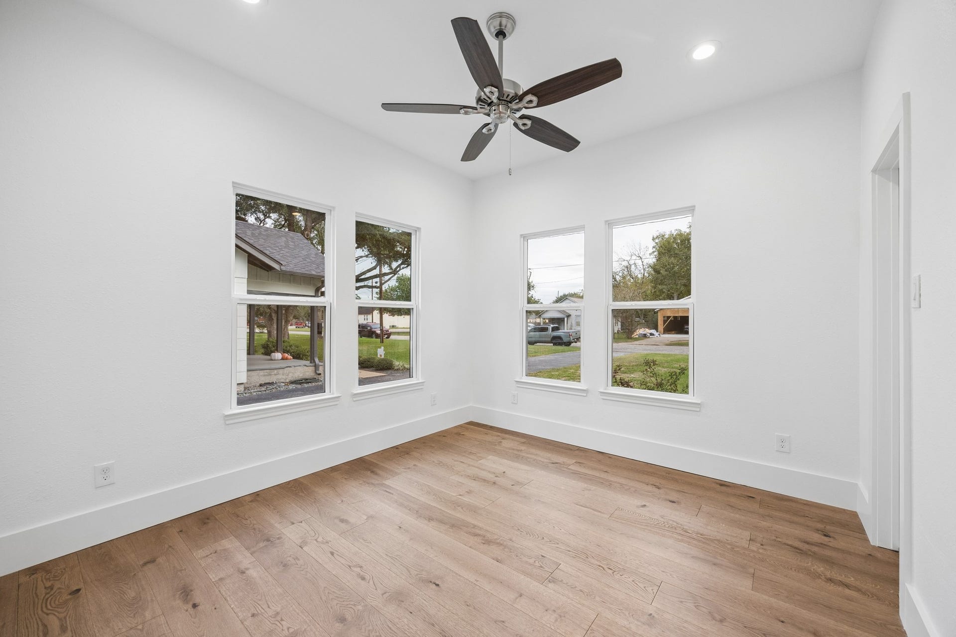 711 4th Street, Sealy, TX 77474 Bright and airy bedroom with large windows, wood flooring, and a stylish ceiling fan.