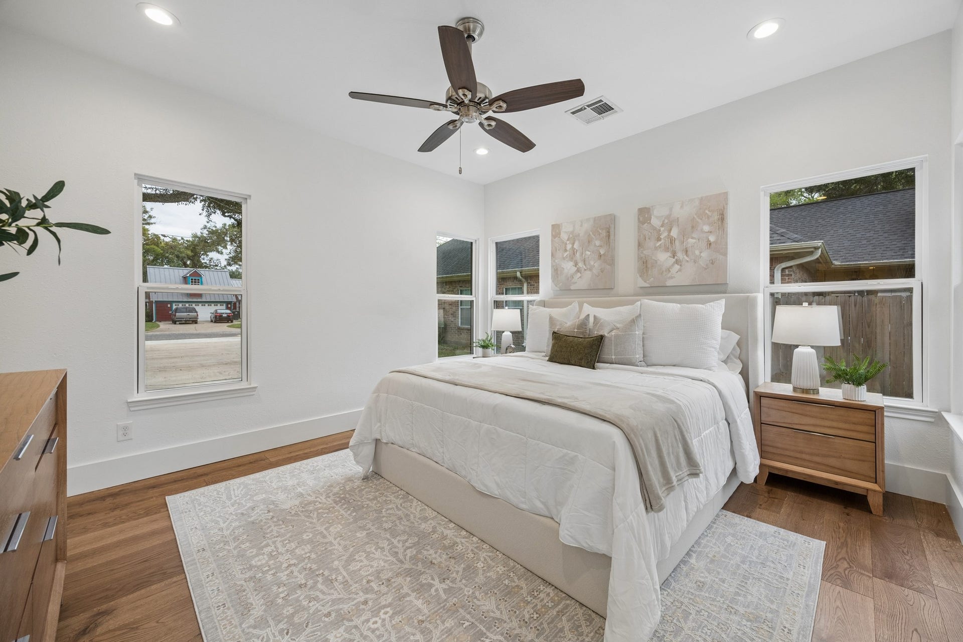711 4th Street, Sealy, TX 77474 Primary bedroom featuring hardwood floors, large windows, and a ceiling fan.