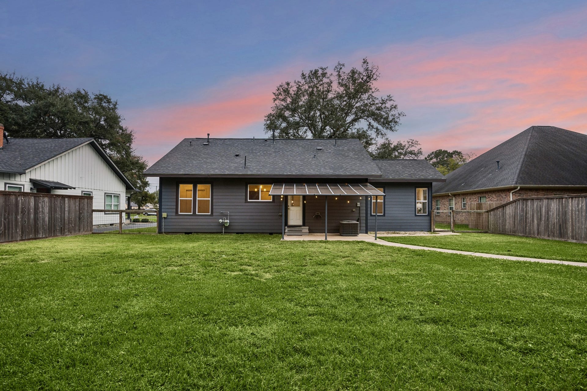 711 4th Street, Sealy, TX 77474 Charming backyard with a spacious lawn and a cozy covered patio, perfect for outdoor relaxation.