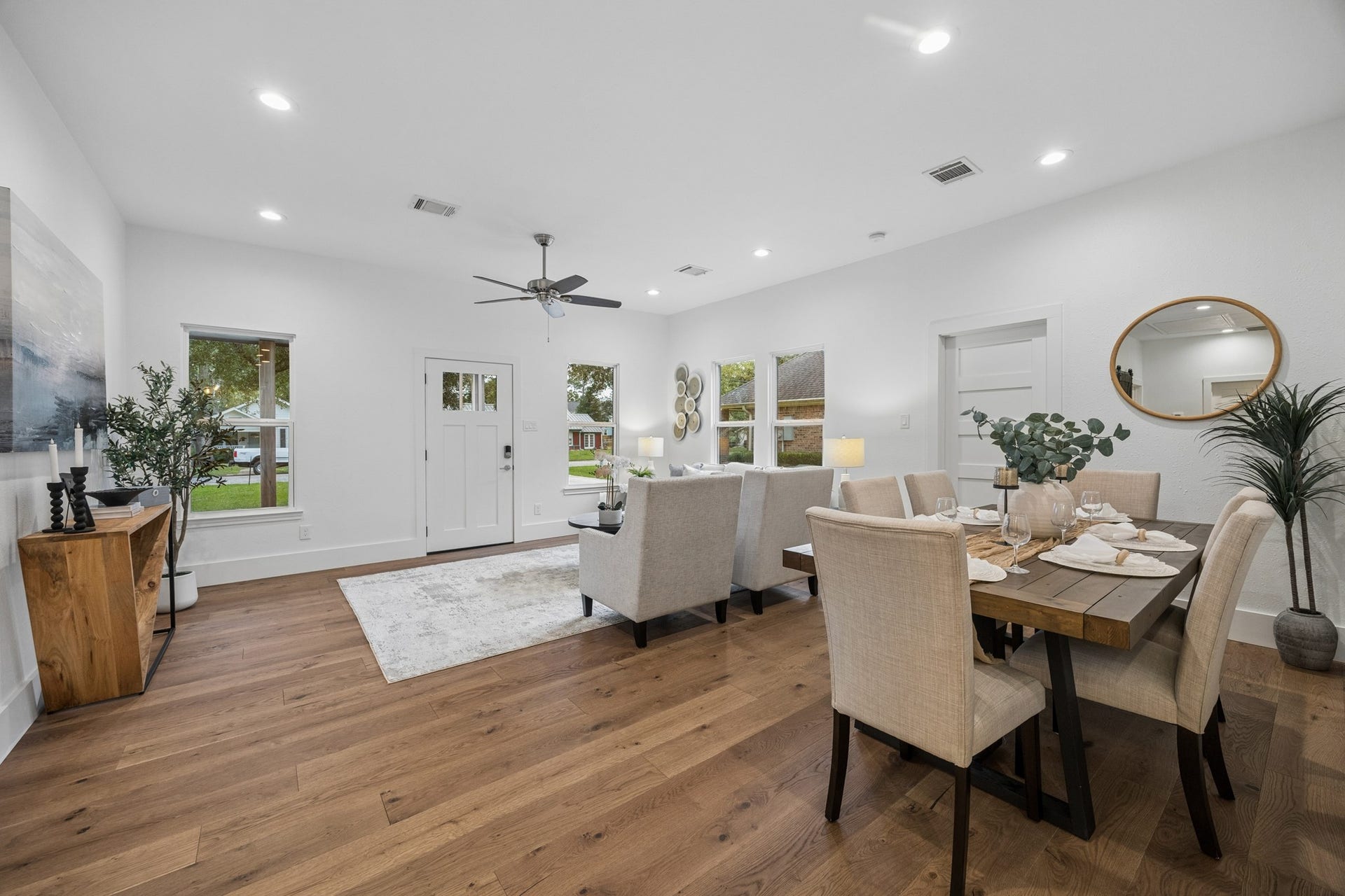 711 4th Street, Sealy, TX 77474 Open-concept living and dining area features elegant wood flooring, neutral tones, and ample natural light, creating a warm and welcoming atmosphere.