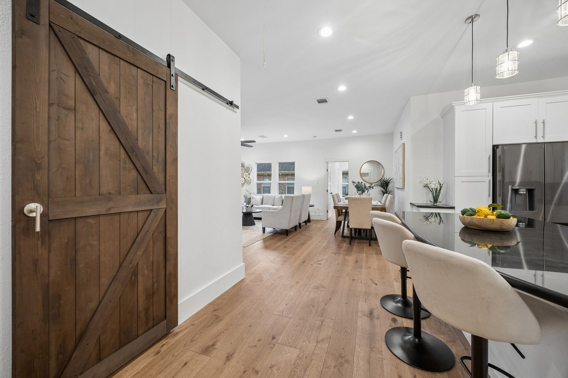 711 4th Street, Sealy, TX 77474 Elegant open-concept living area featuring a modern kitchen with sleek bar seating, a rustic sliding barn door, and a spacious dining area perfect for entertaining.
