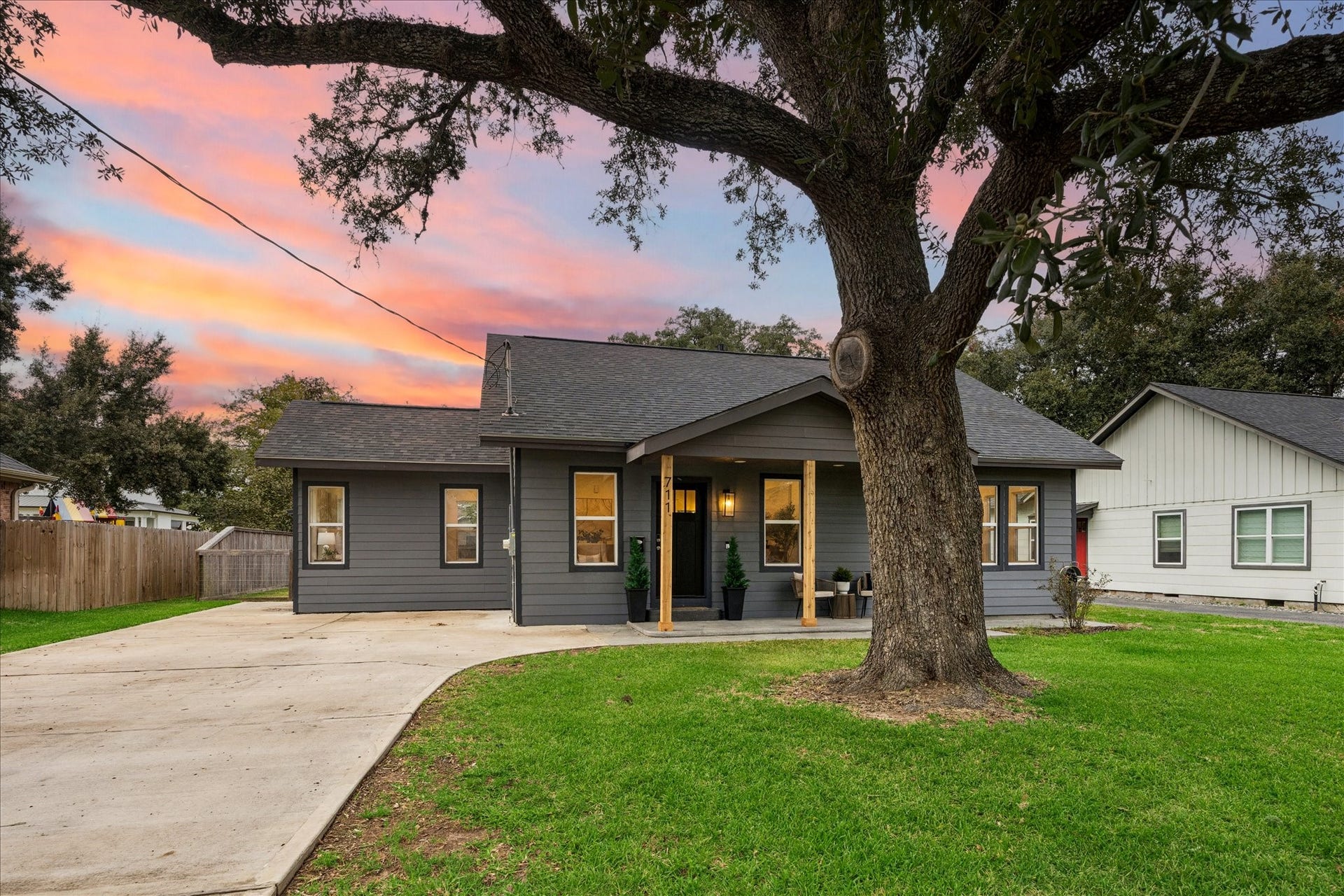 711 4th Street, Sealy, TX 77474 Charming home with modern accents features a sleek black door, elegant lighting, cedar beam posts, and covered sitting area.