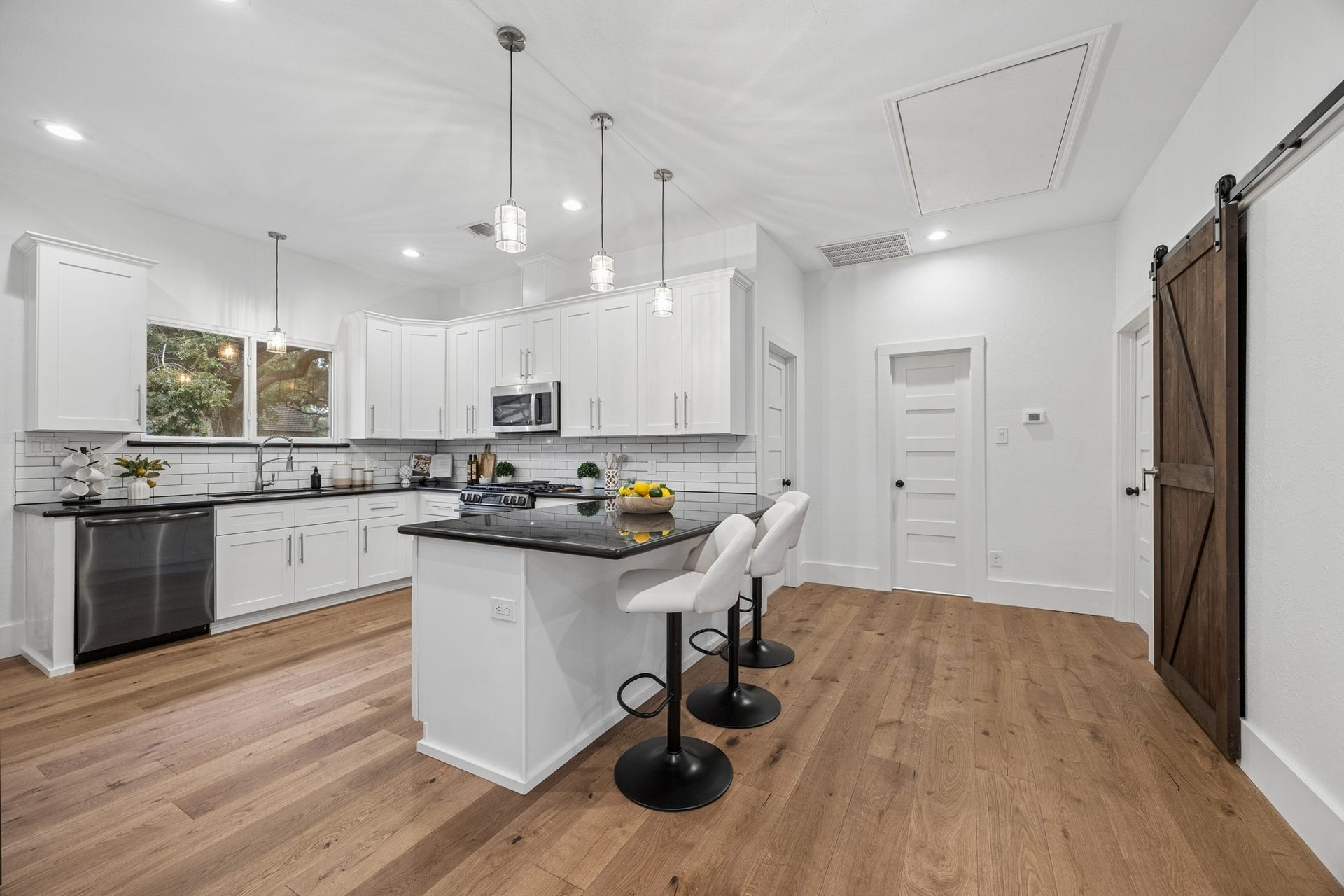 711 4th Street, Sealy, TX 77474 Modern kitchen with sleek white cabinetry, stainless steel appliances, and a stylish subway tile backsplash. Features an inviting island with seating and elegant pendant lighting.