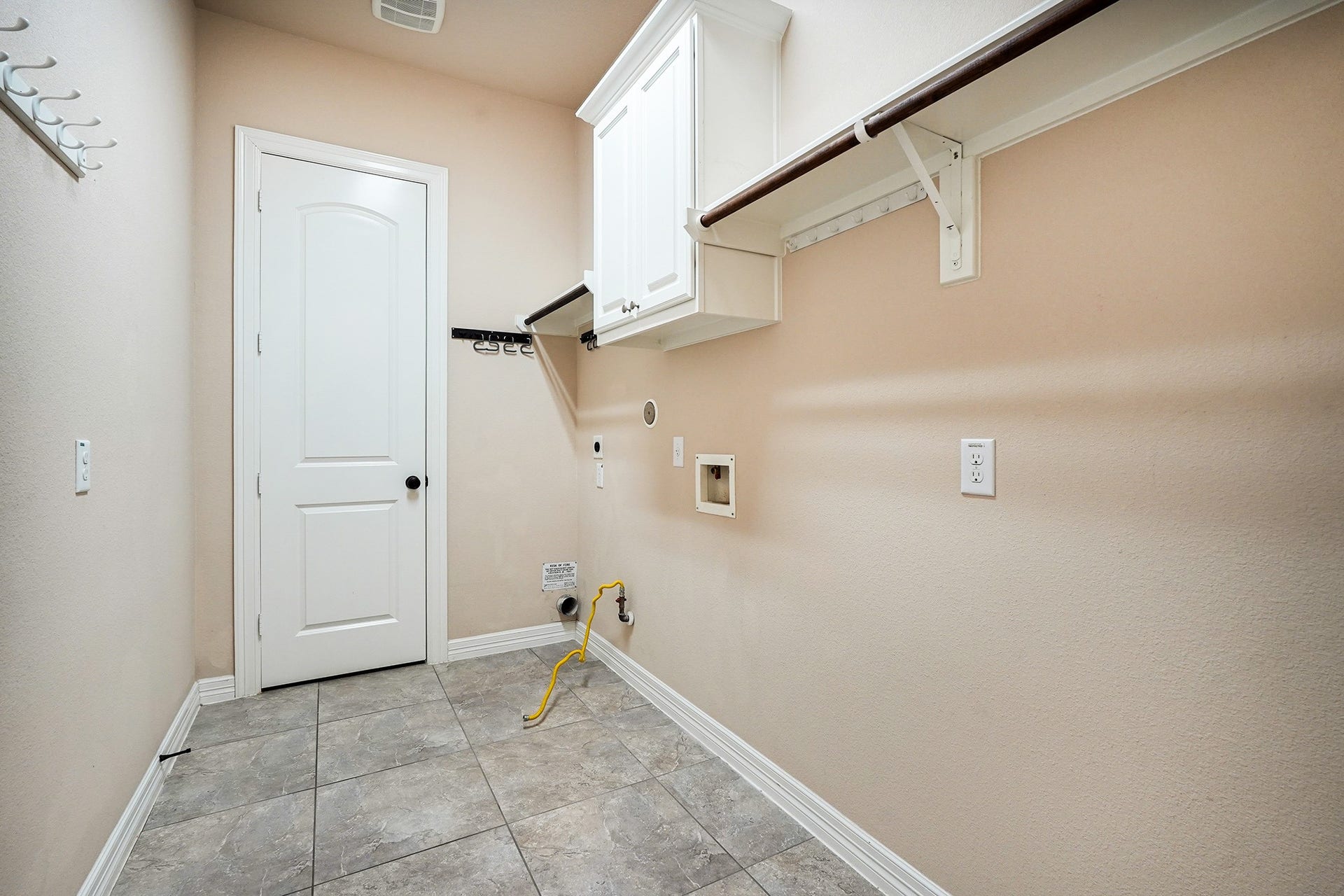 3102 Barrons Way, Sugar Land, TX 77479 This oversized laundry room with tiled flooring, a white door, wall-mounted cabinets, and connections for a washer and dryer features ample shelving for storage.