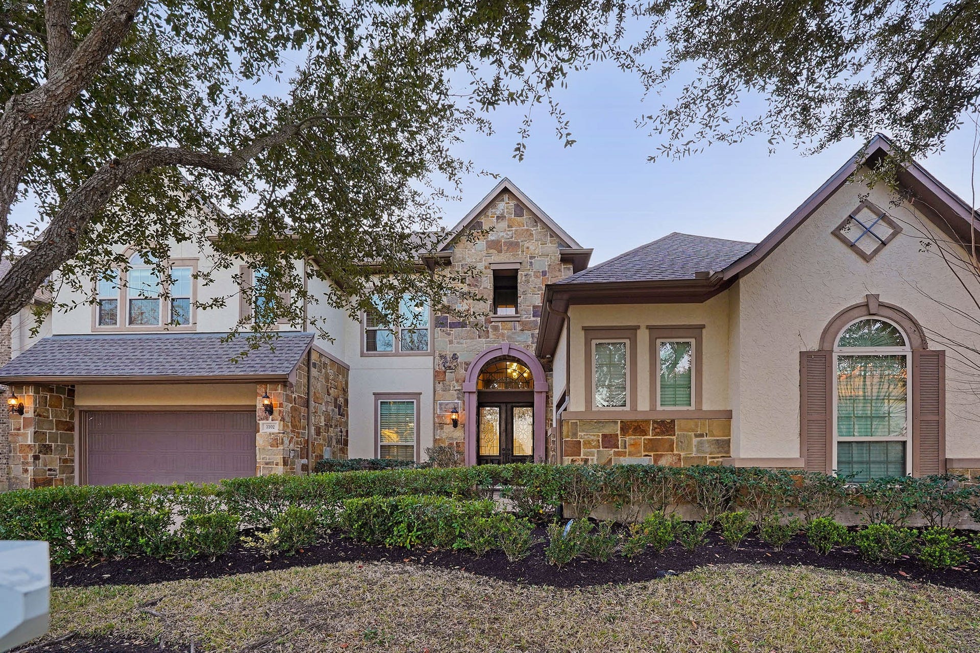 3102 Barrons Way, Sugar Land, TX 77479 This elegant two-story, 5br-4.5ba home features a stone & stucco exterior, with a welcoming arched entryway and well-maintained landscaping. The attached 3-car garage and large windows enhance its curb appeal, nestled under mature trees.