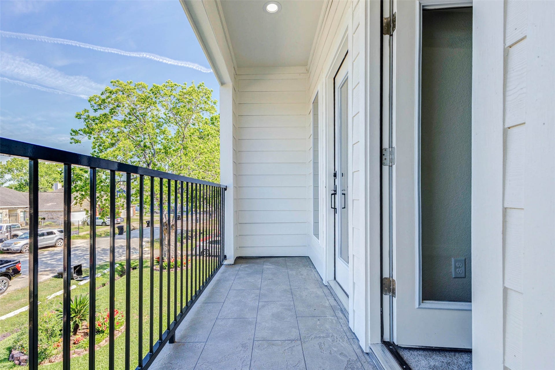The second-story balcony is finished with durable stone-patterned tiling and a secure wrought-iron safety railing.