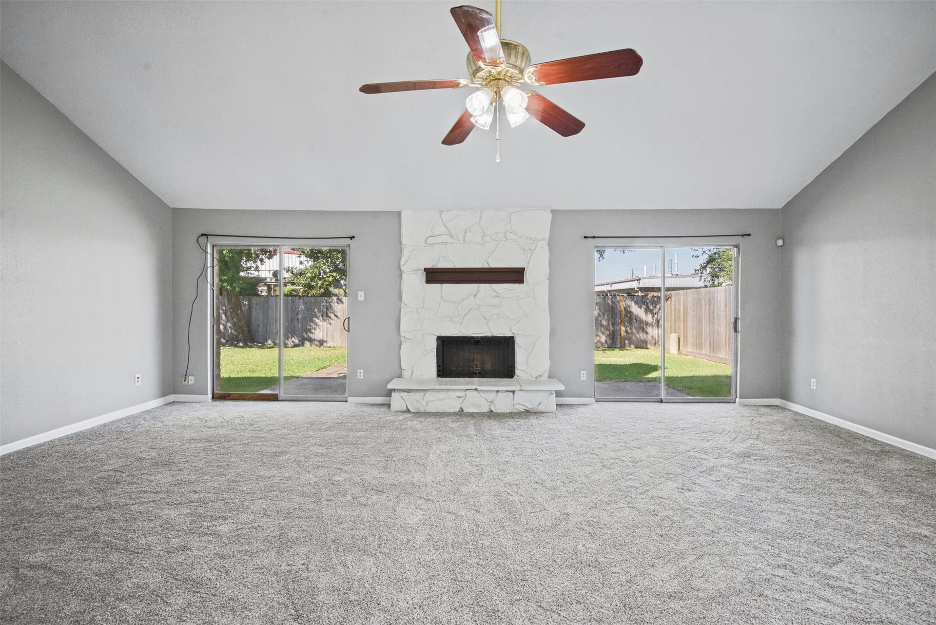 1323 Castle Glen Drive, Houston, TX 77015 The heart of the home! Gather around the striking stone fireplace in this expansive living room, featuring vaulted ceilings, plush carpeting, and two sliding glass doors that bring in natural light and offer easy access to the backyard.