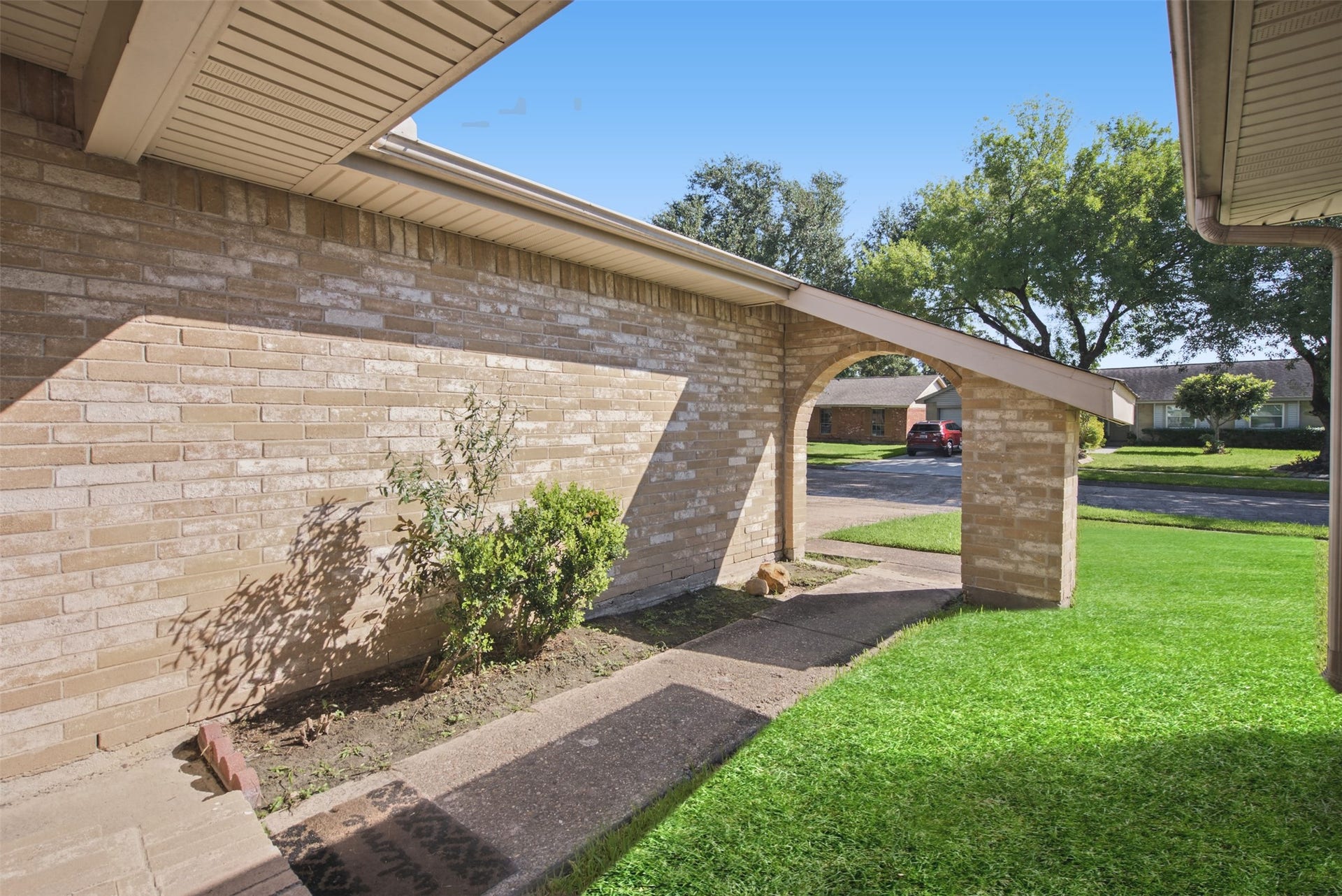 1323 Castle Glen Drive, Houston, TX 77015 A warm welcome begins here! Follow the covered walkway beneath a charming brick archway, offering a sheltered approach to your front door.