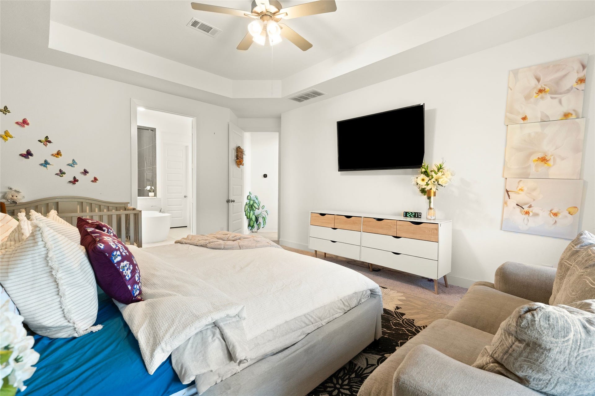 11111 Zinnias Court, Cypress, TX 77433 Soft natural light, a tray ceiling, and a striking accent wall make this primary bedroom feel like a private escape.