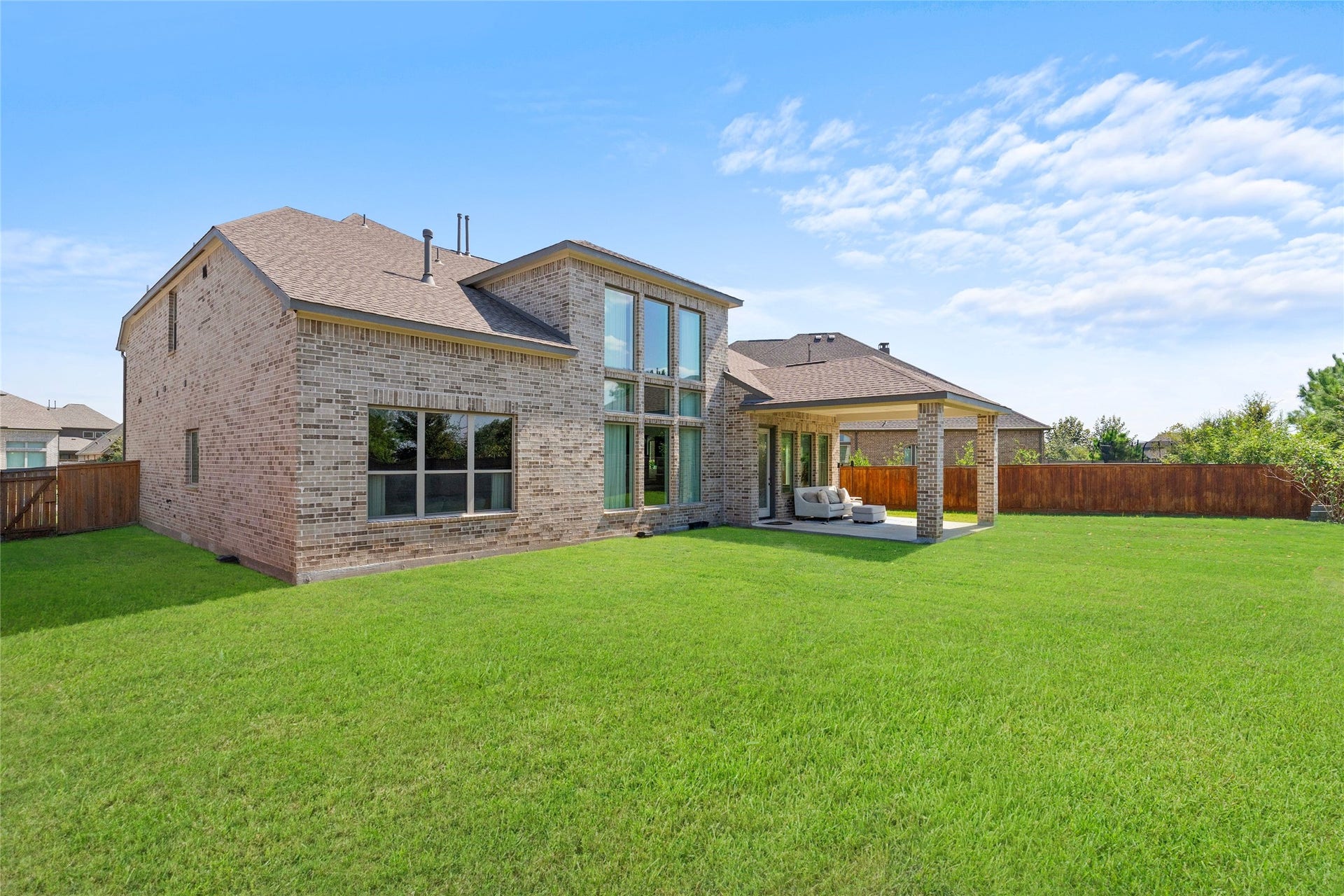 11111 Zinnias Court, Cypress, TX 77433 This elevated view showcases the impressive rear architecture, tall windows, covered patio, and generous lawn framed by fencing.