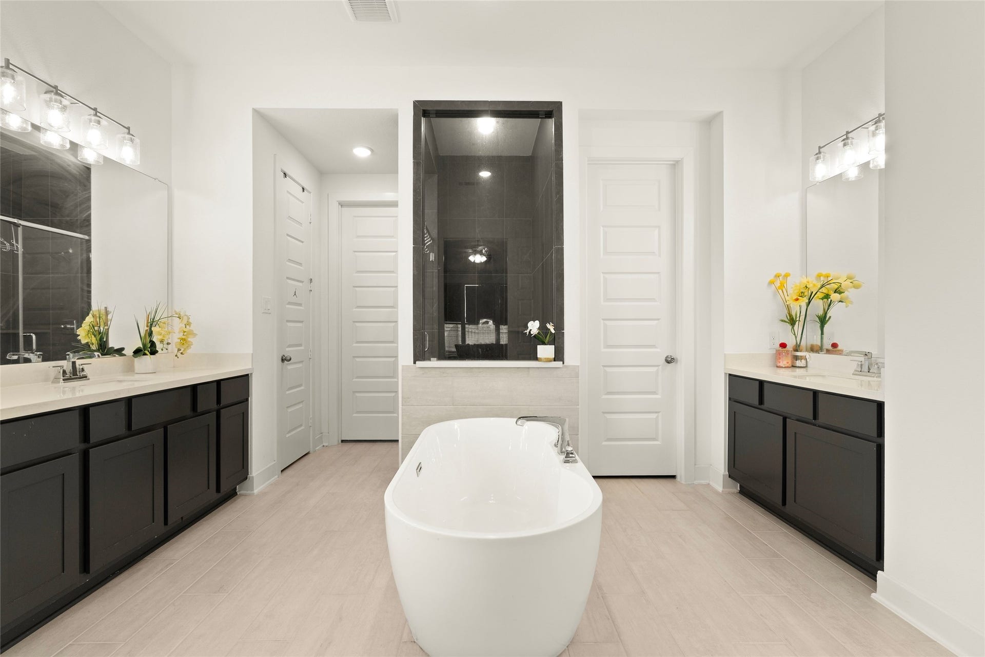 11111 Zinnias Court, Cypress, TX 77433 A freestanding soaking tub takes center stage in this beautiful primary bathroom, accompanied by separate vanities and an impressive walk-in shower.